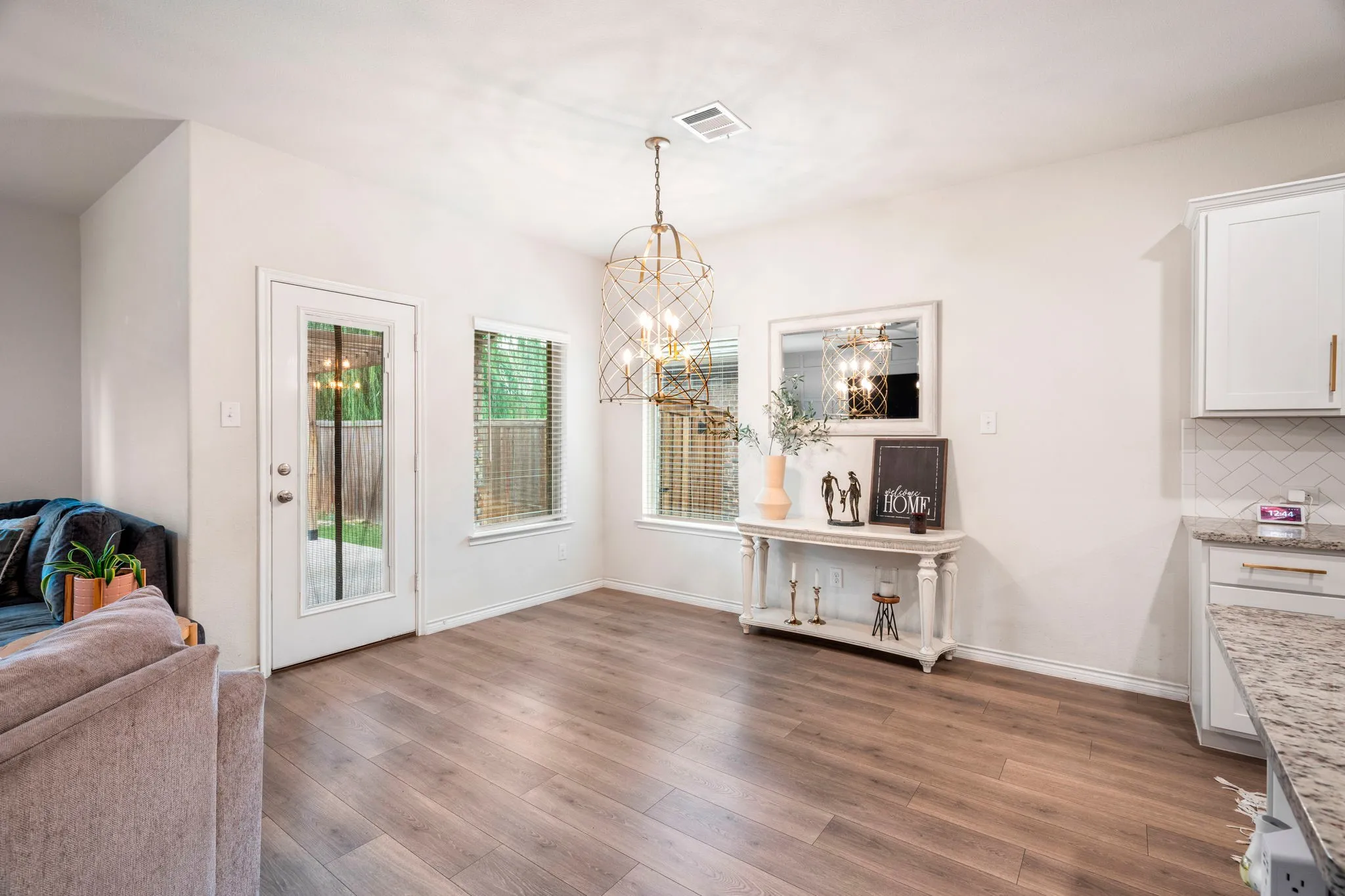Spacious dining area featuring wood-finish flooring, a contemporary chandelier, and ample natural light from multiple windows
