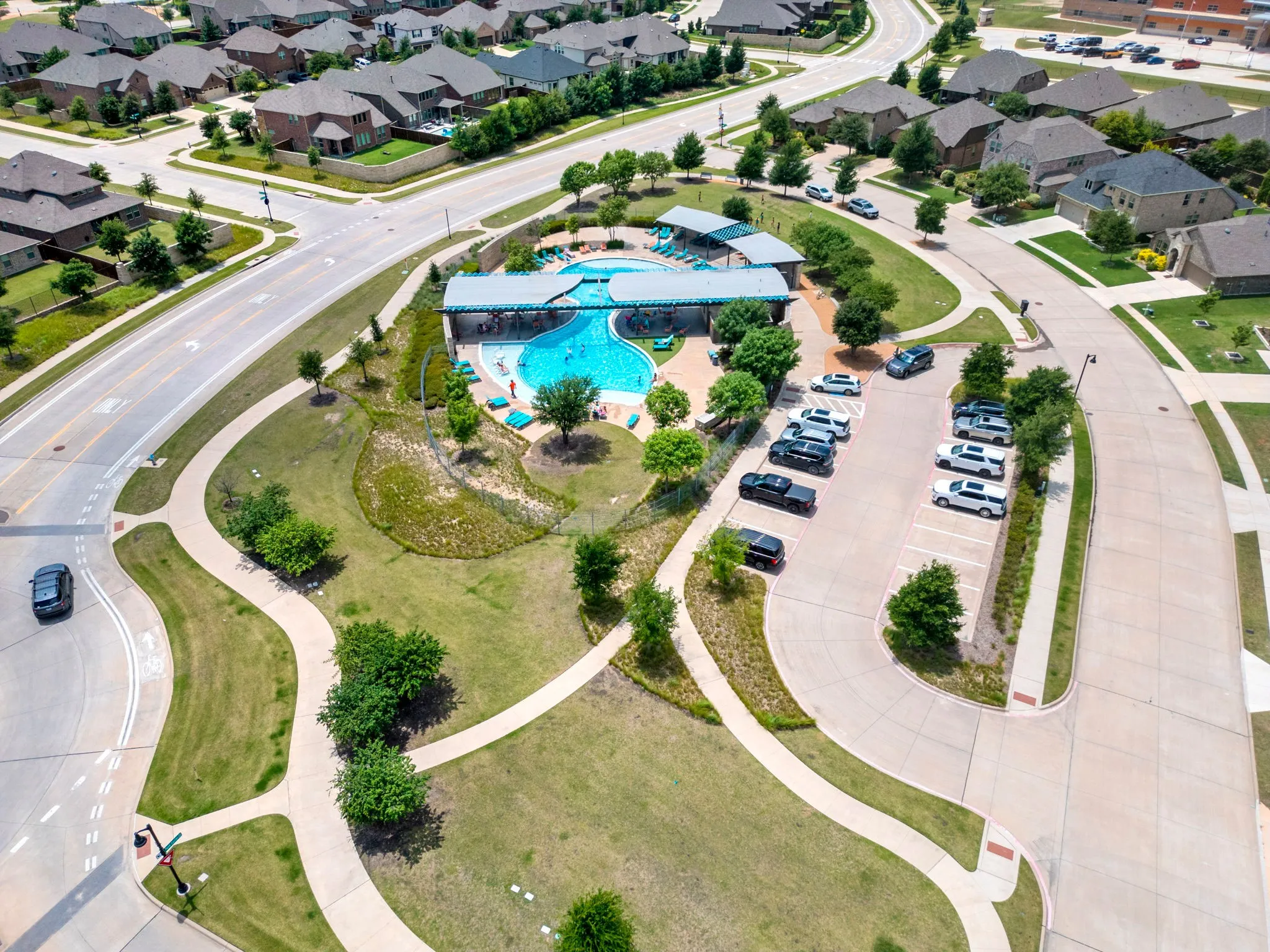 Community amenities featuring a large swimming pool with surrounding lounge chairs, covered patio, and adjacent parking lot