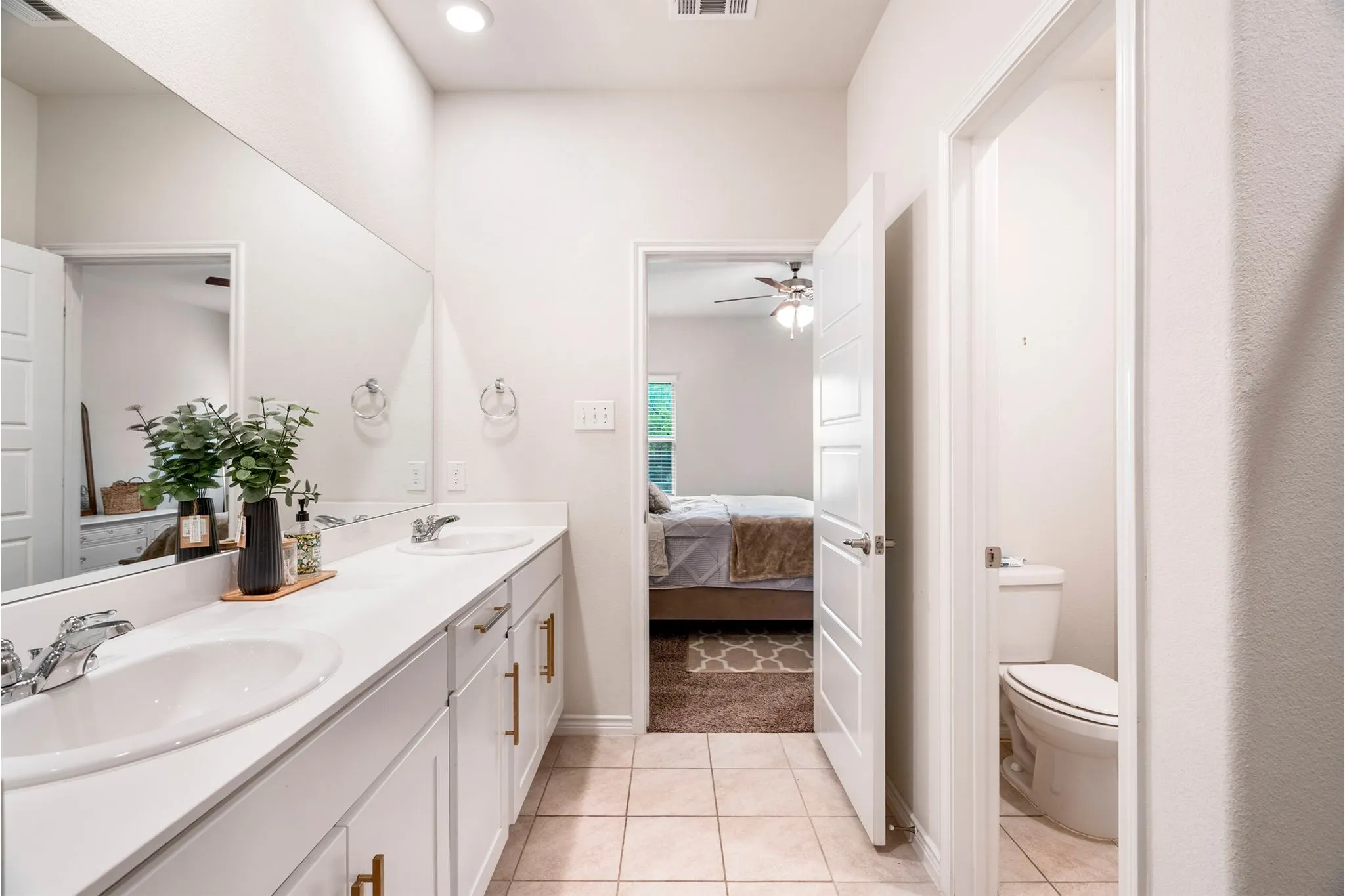 Double vanity with undermount sinks, chrome fixtures, white cabinetry, and gold-tone hardware