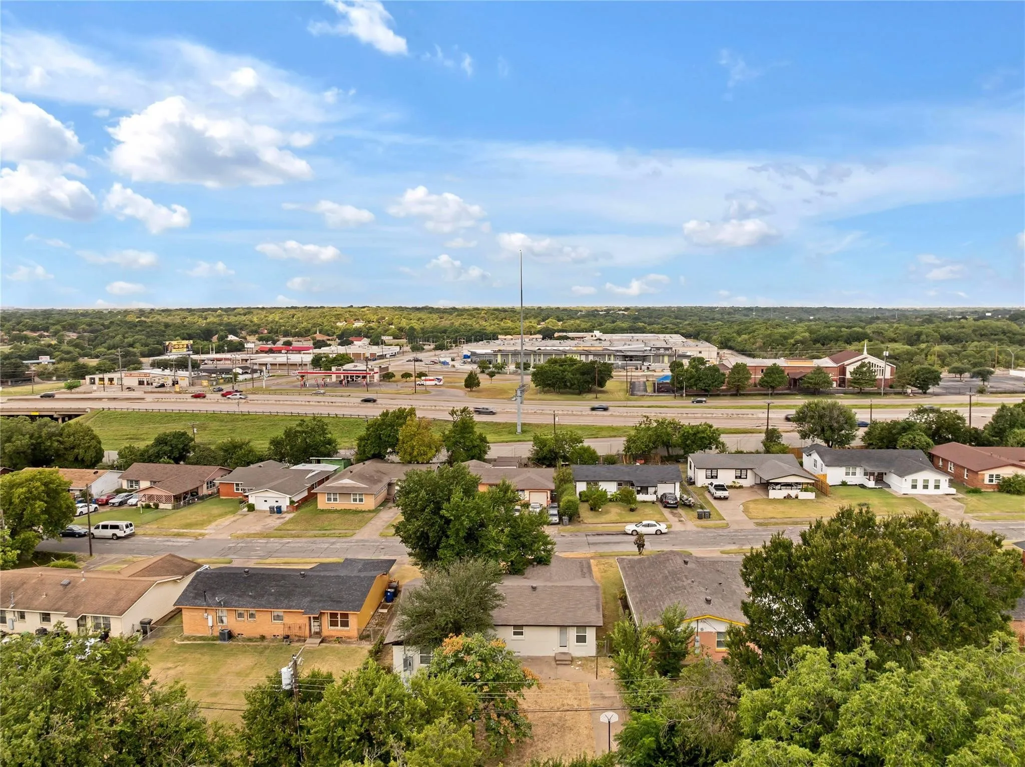 Aerial perspective showcasing residential properties and a commercial strip with a multi-lane highway