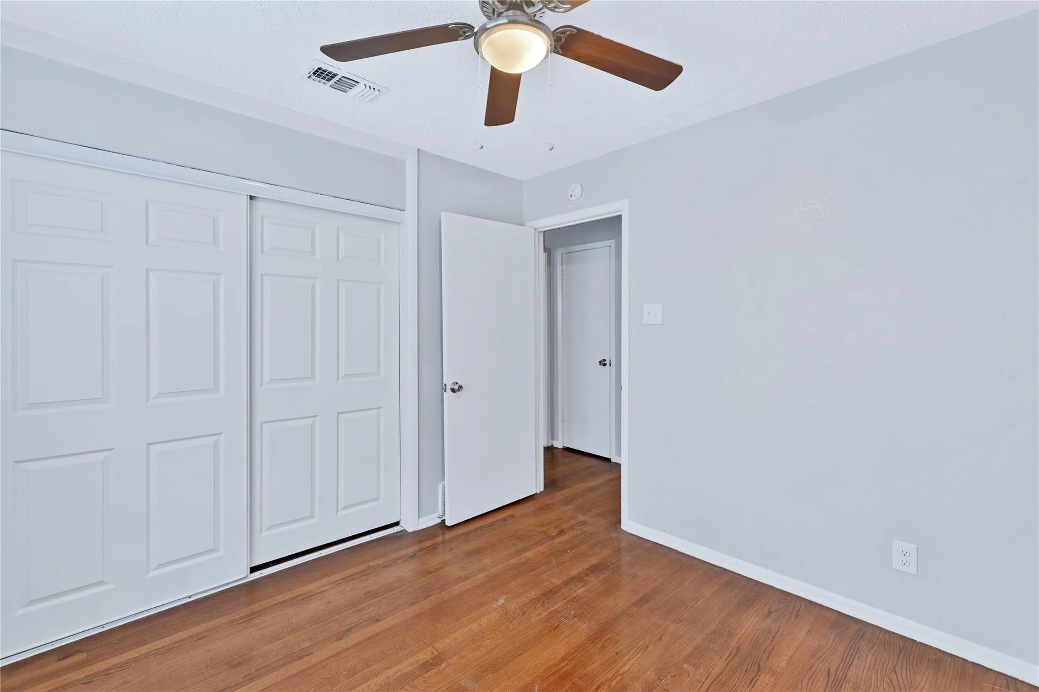 Room featuring wood-finish flooring, white baseboards, and a ceiling fan with integrated lighting
