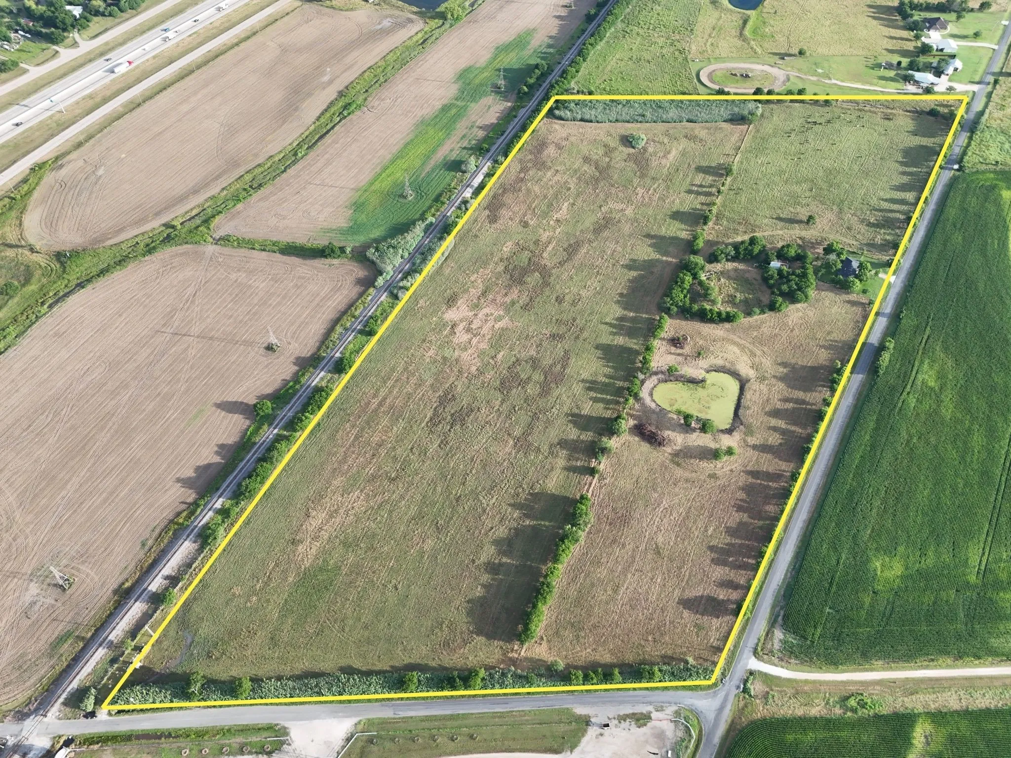 Expansive acreage featuring mixed terrain, a prominent heart-shaped pond, and several mature trees