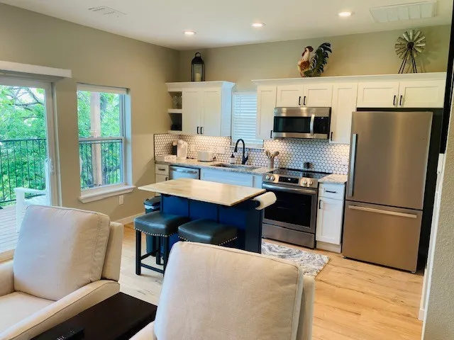 Kitchen with stainless steel appliances, white cabinets, light countertops, tasteful backsplash, and recessed lighting