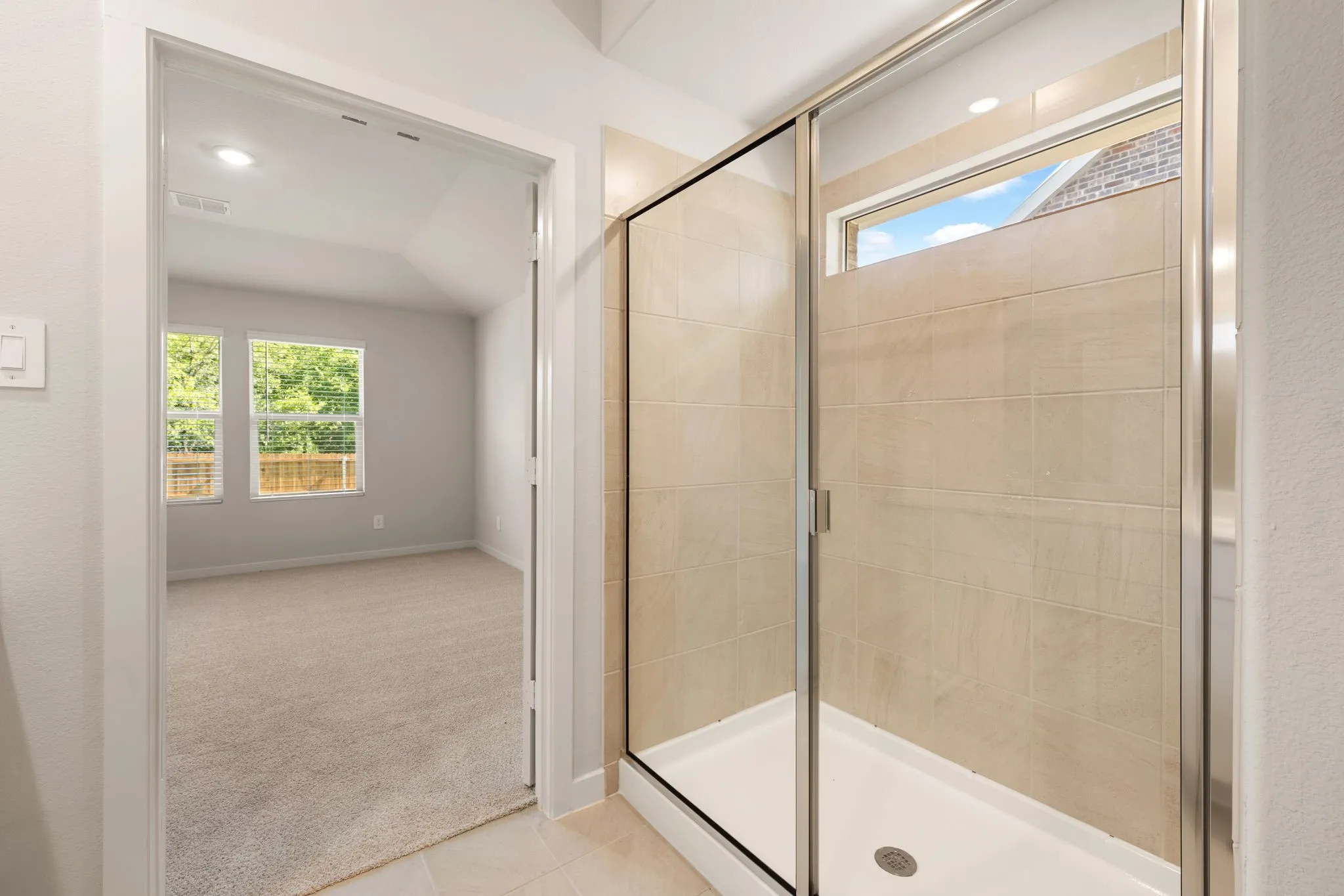 Walk-in shower with tiled walls, clear glass enclosure, and transom window