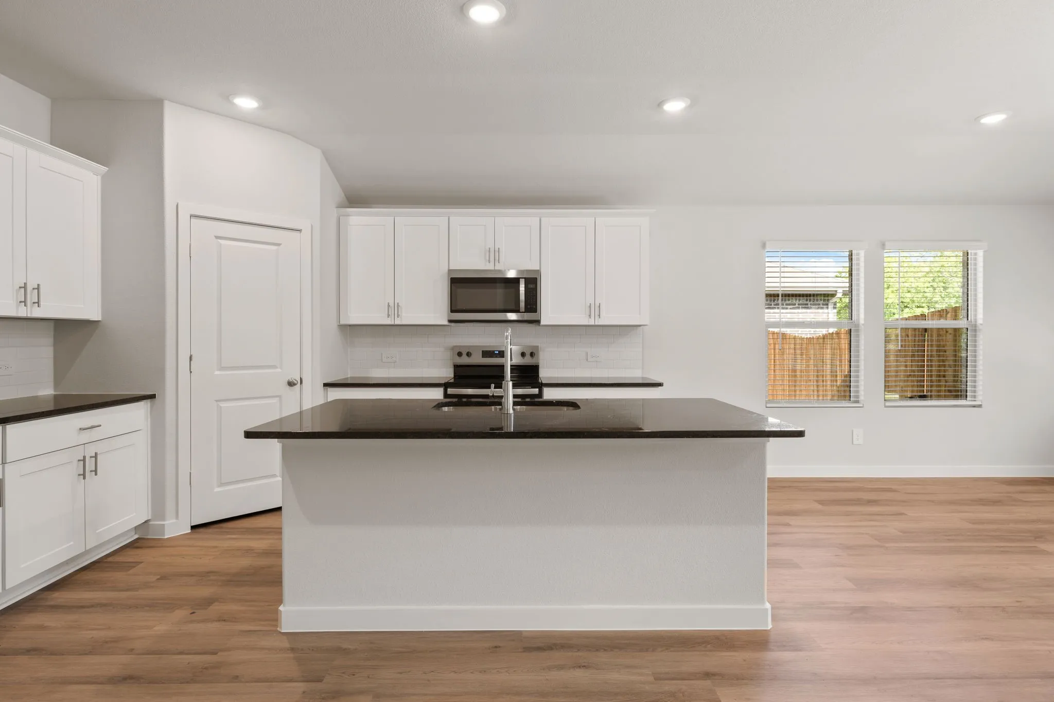 Modern kitchen featuring white shaker cabinetry, dark countertops, and stainless steel appliances