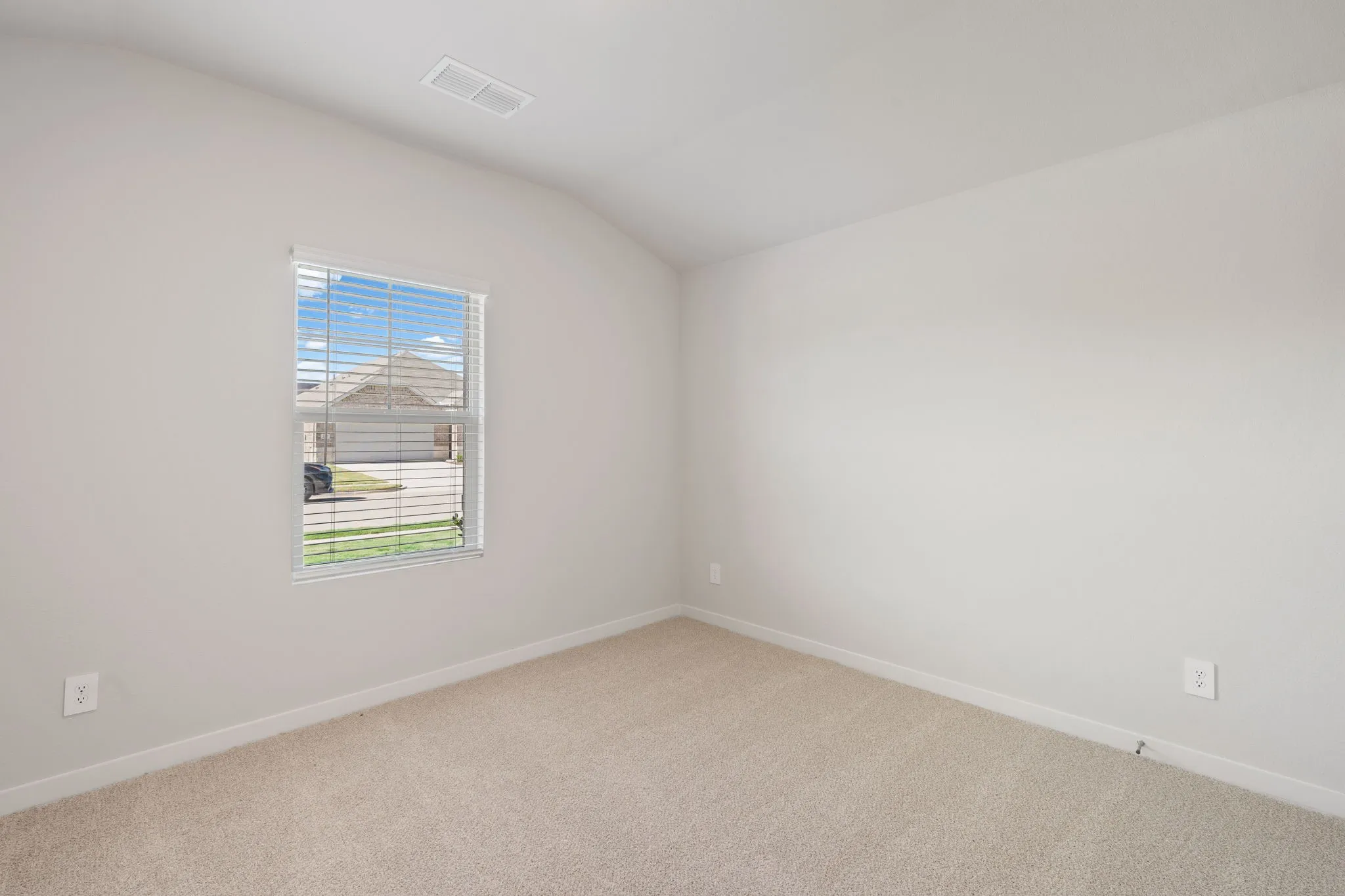 Neutral-toned room featuring a single window with horizontal blinds, light beige carpeting, and white baseboards