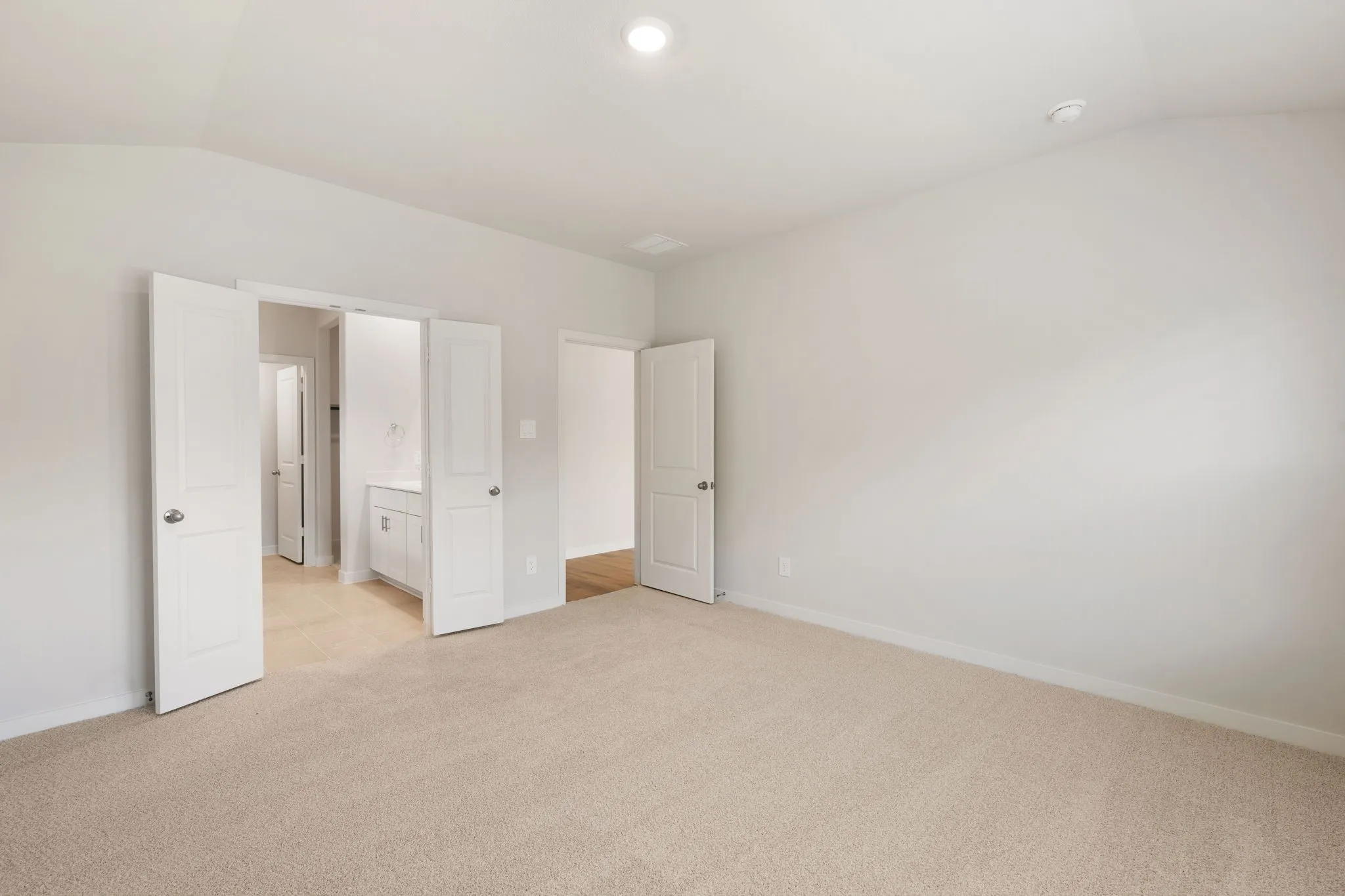 Spacious room featuring neutral carpeting, light gray walls, and recessed lighting