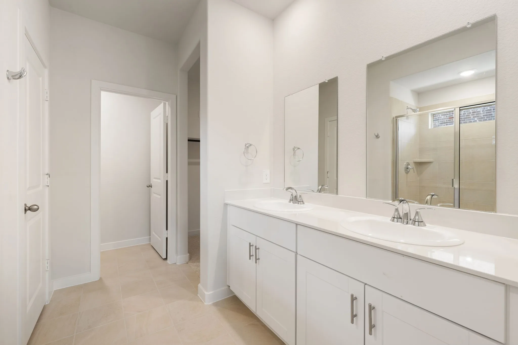 Bathroom featuring a double vanity with white cabinetry, integrated sinks, and polished chrome fixtures