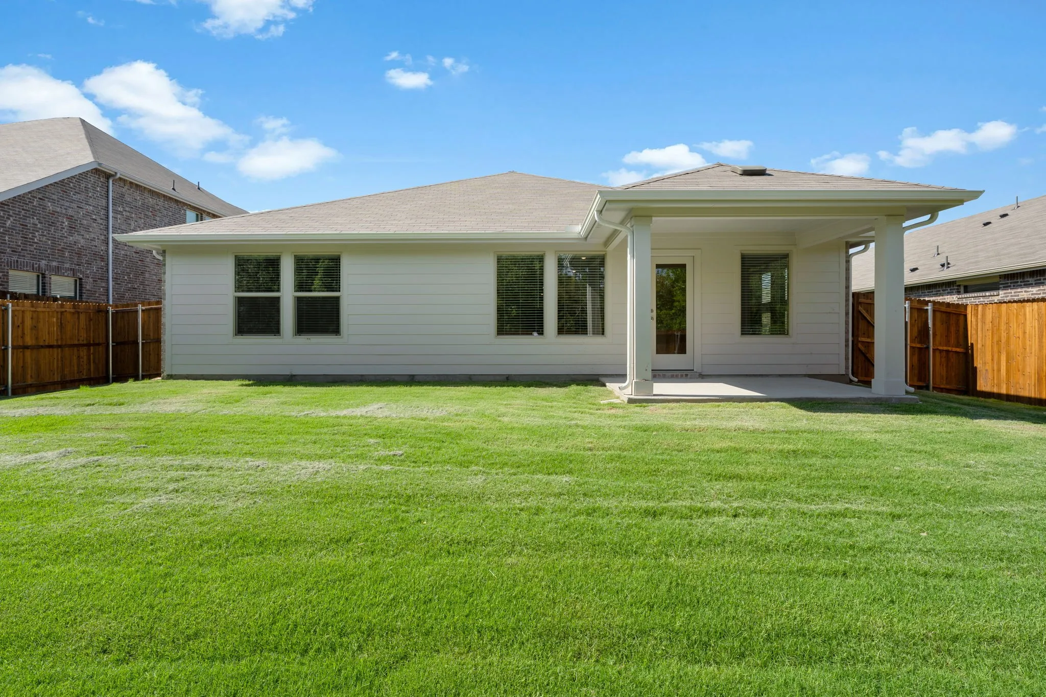 Expansive green lawn with a covered patio featuring white columns