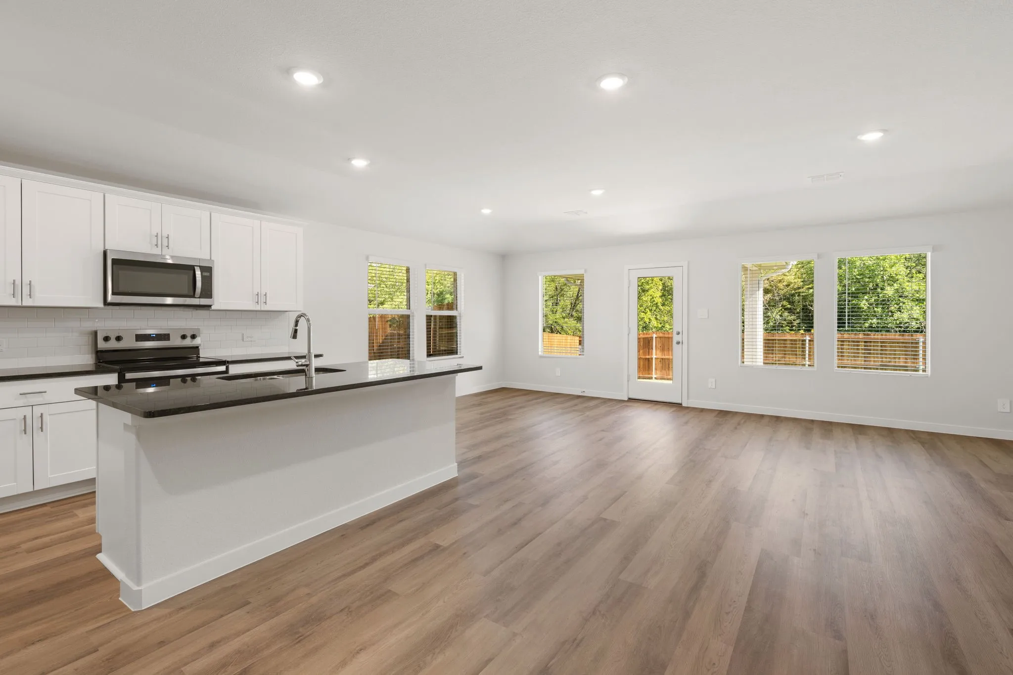 Open-concept living area with wood-finish flooring, recessed lighting, and multiple windows