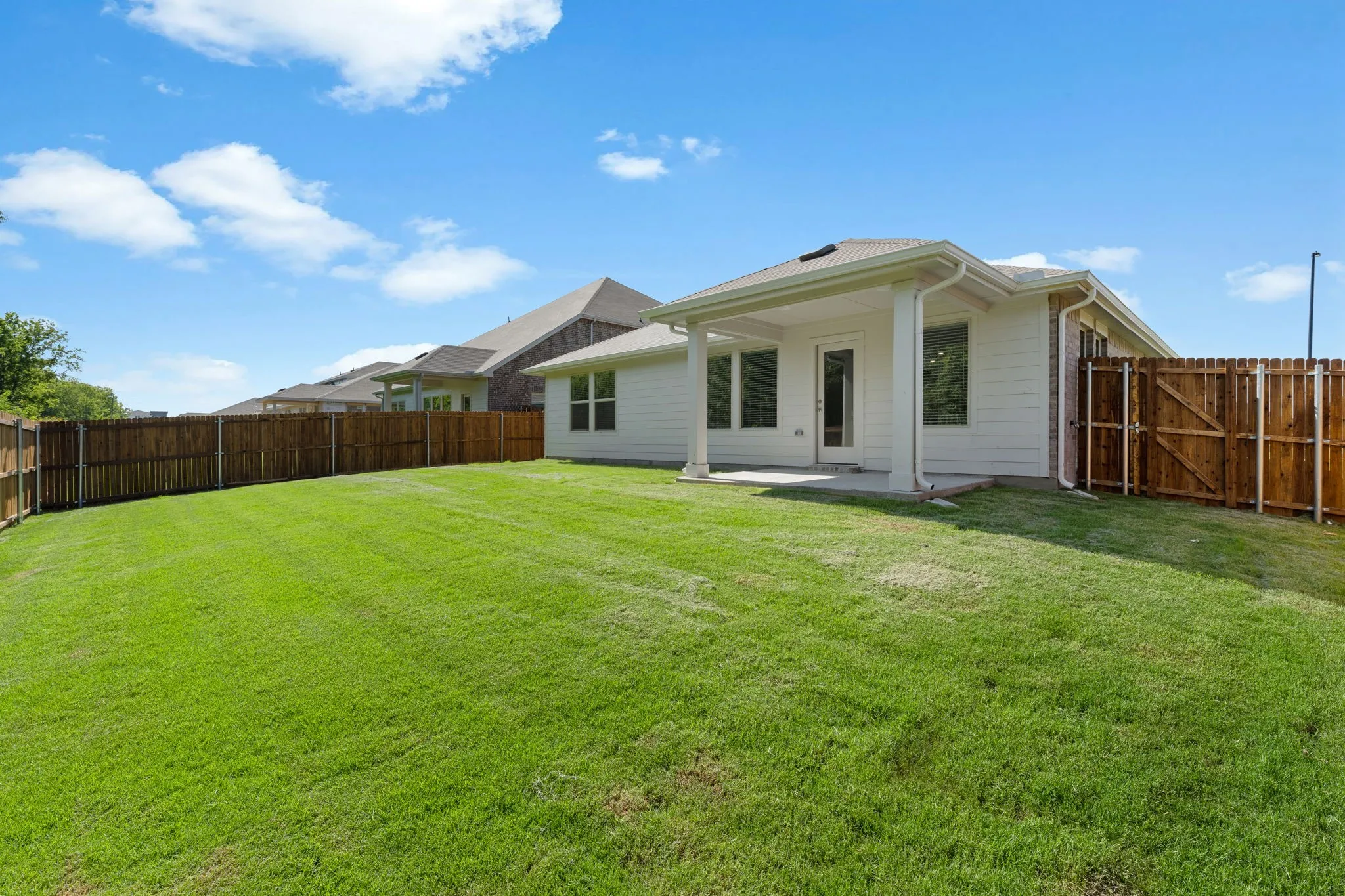 Expansive fenced backyard featuring a covered patio, a concrete slab, and a wood privacy fence