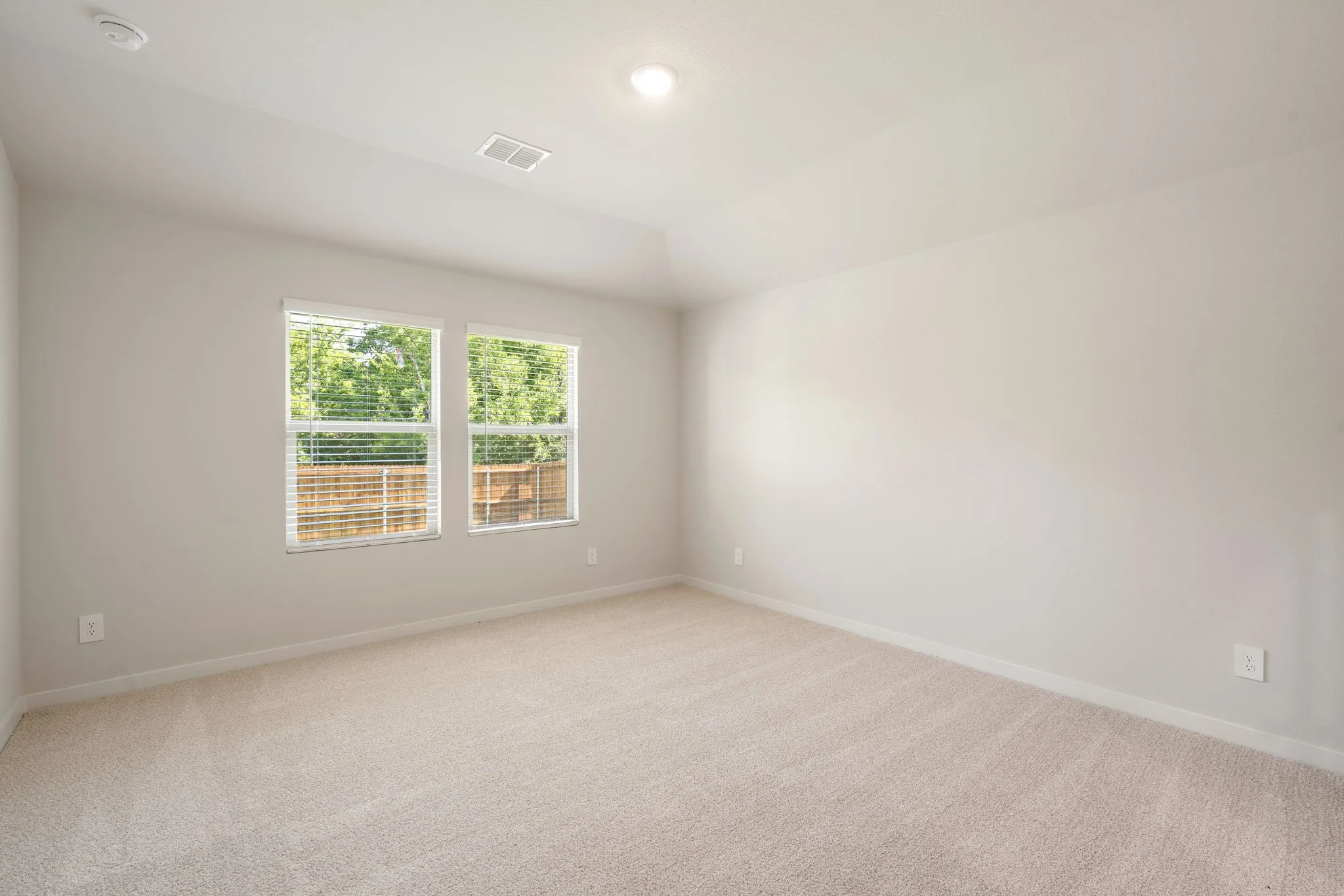Carpeted room featuring two windows with horizontal blinds, light-colored walls, and recessed ceiling lighting
