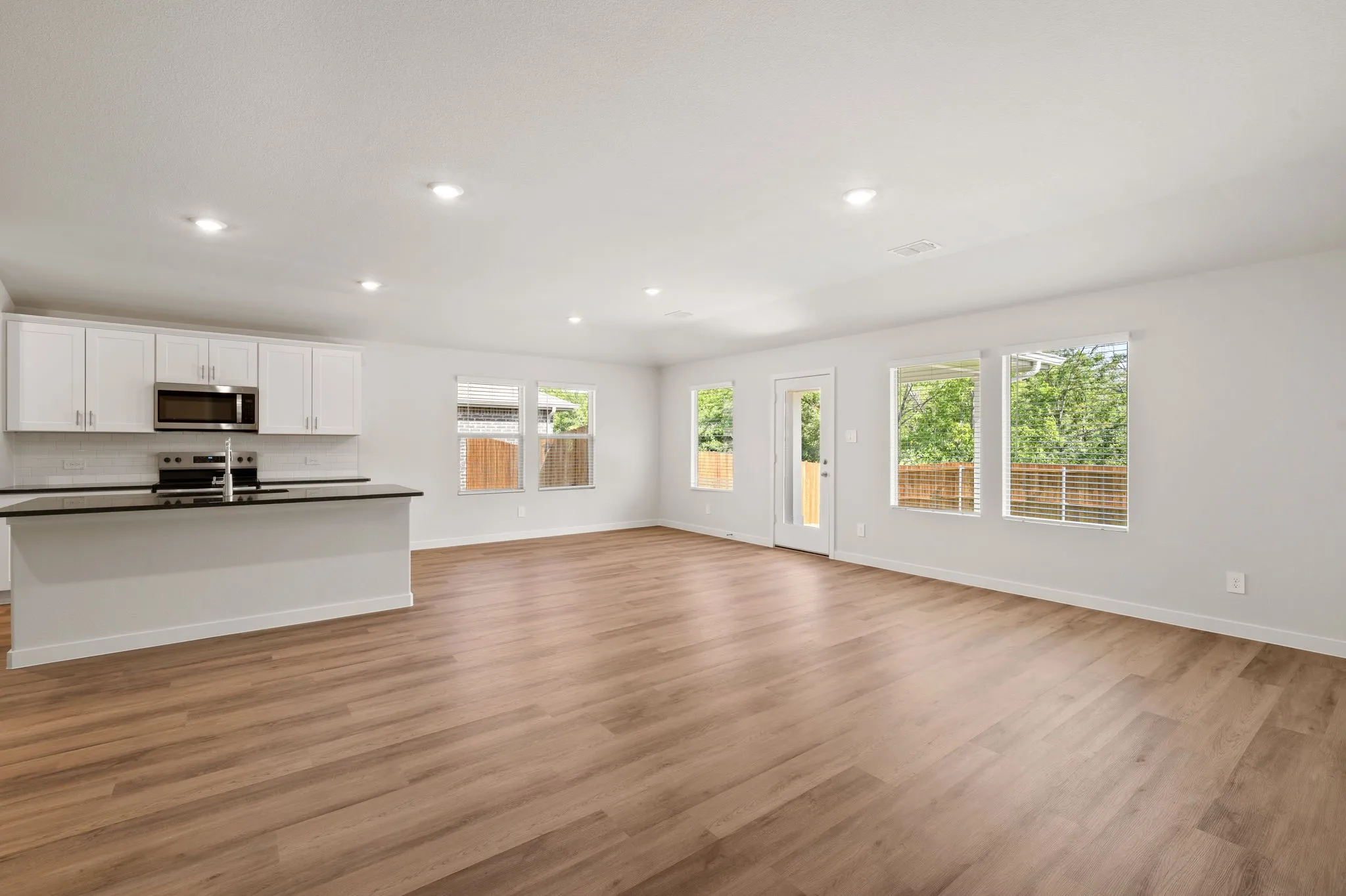Open-concept living space featuring wood-finish flooring, recessed lighting, and multiple windows