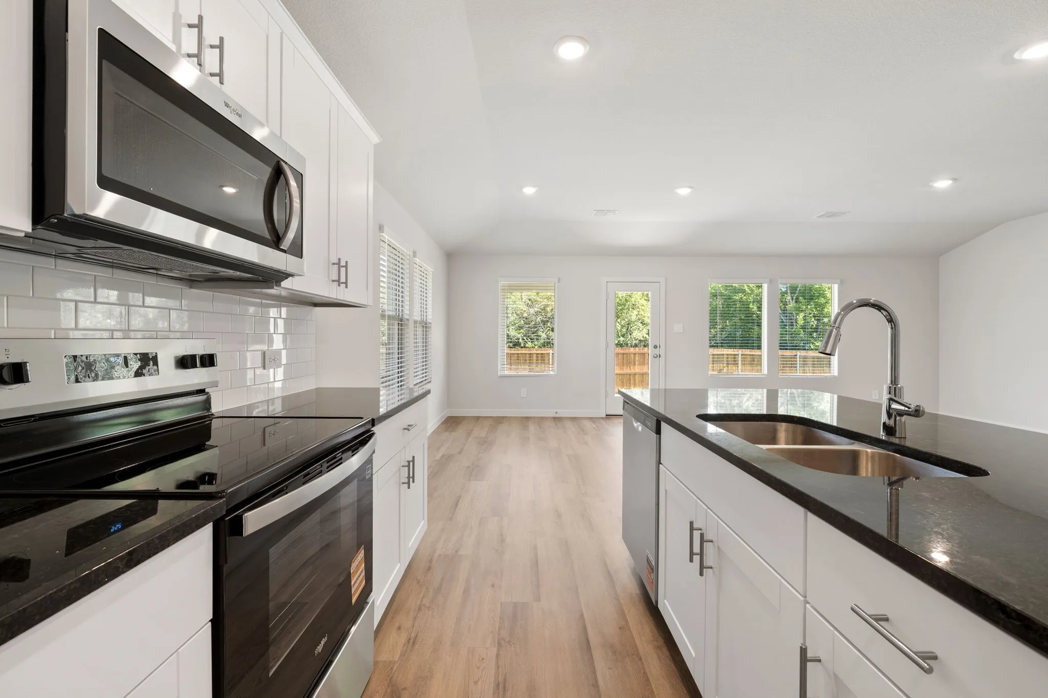Modern kitchen featuring white cabinetry, dark countertops, stainless steel appliances, and a subway tile backsplash