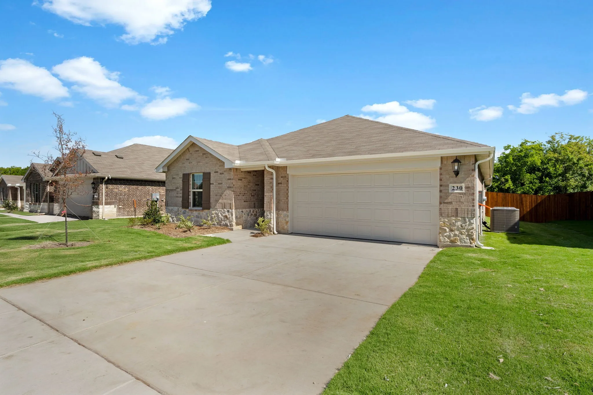 Single-story property featuring a brick and stone facade, attached two-car garage, and a concrete driveway