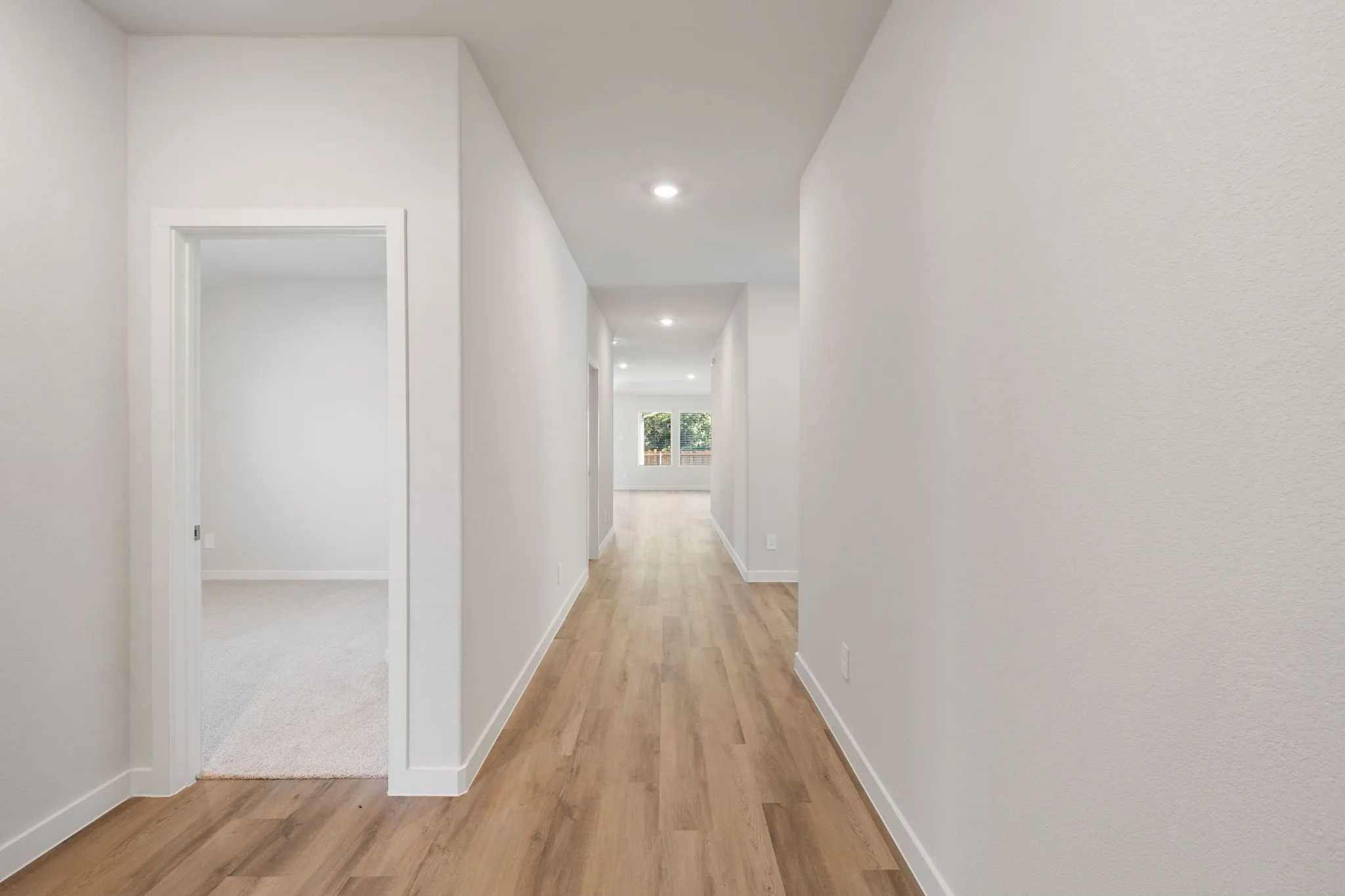 Hallway featuring wood-finish flooring, recessed lighting, and crisp white walls
