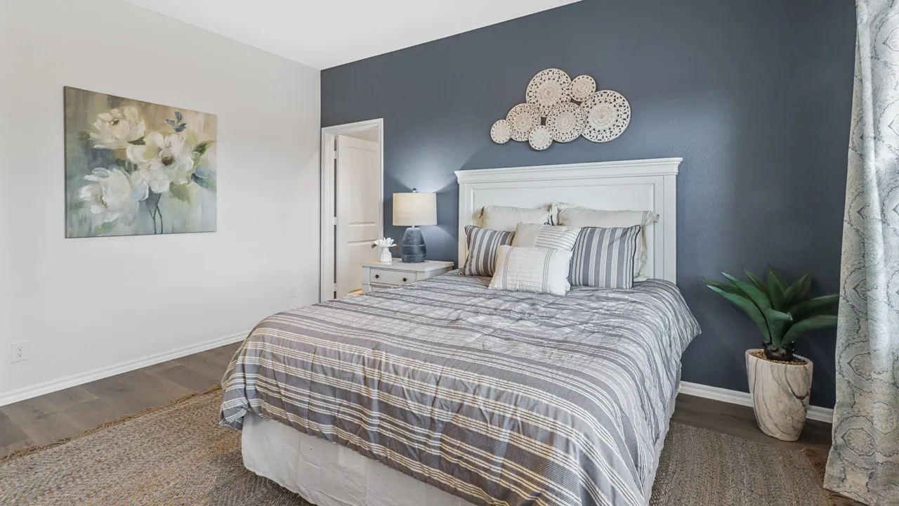 Bedroom featuring a paneled headboard, wood-finish flooring, and white baseboards