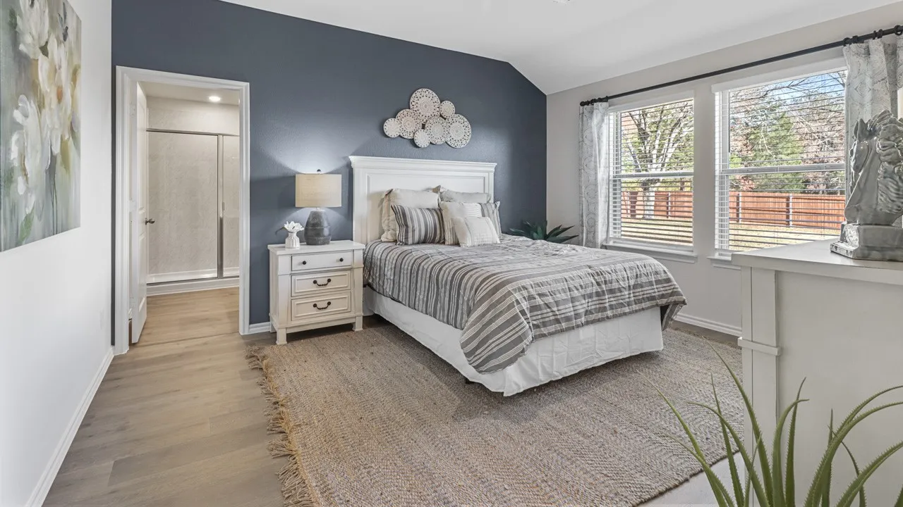 Bedroom featuring wood-finish flooring, a vaulted ceiling, and dual windows with horizontal blinds