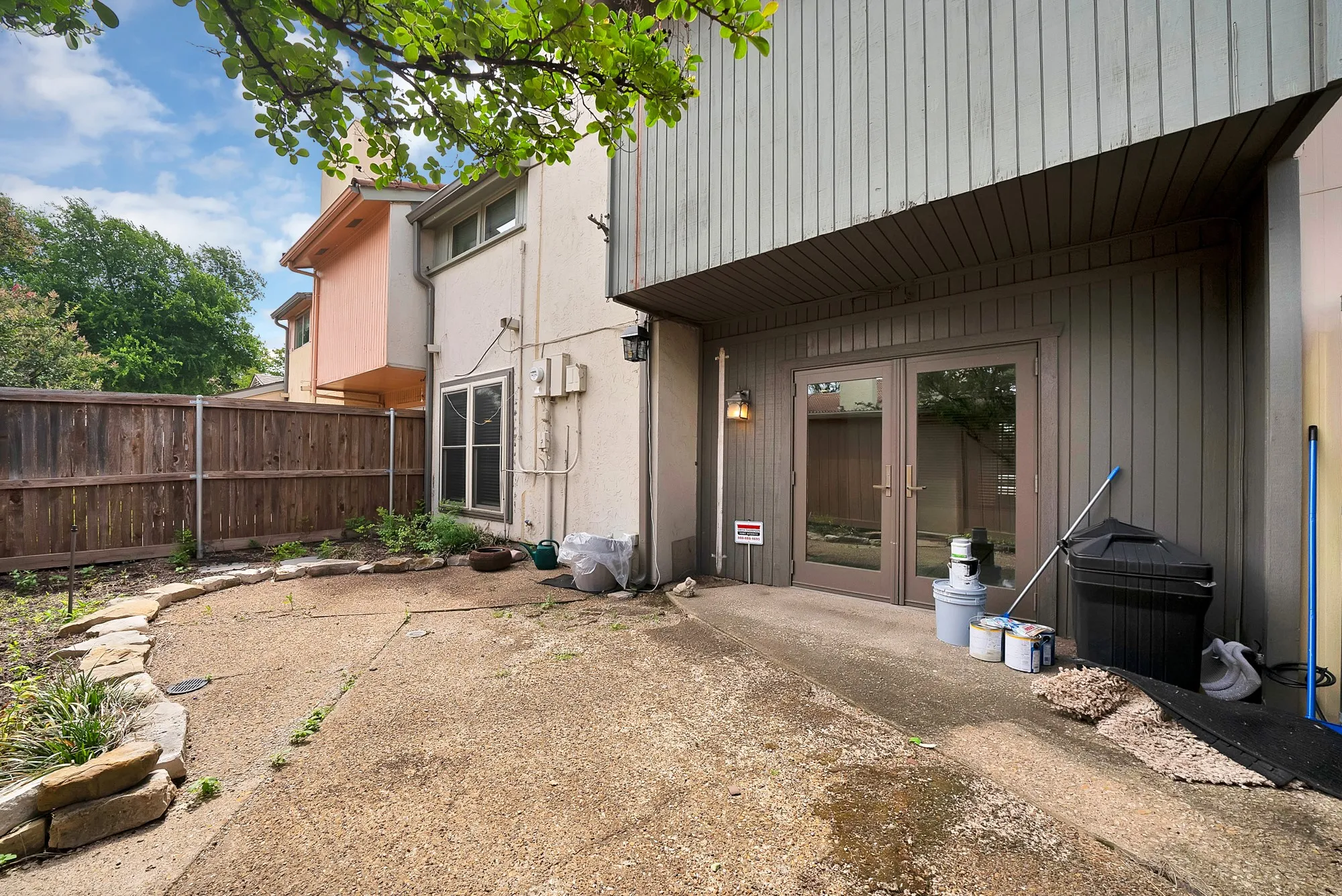 Concrete patio area featuring a stone border and wood privacy fencing