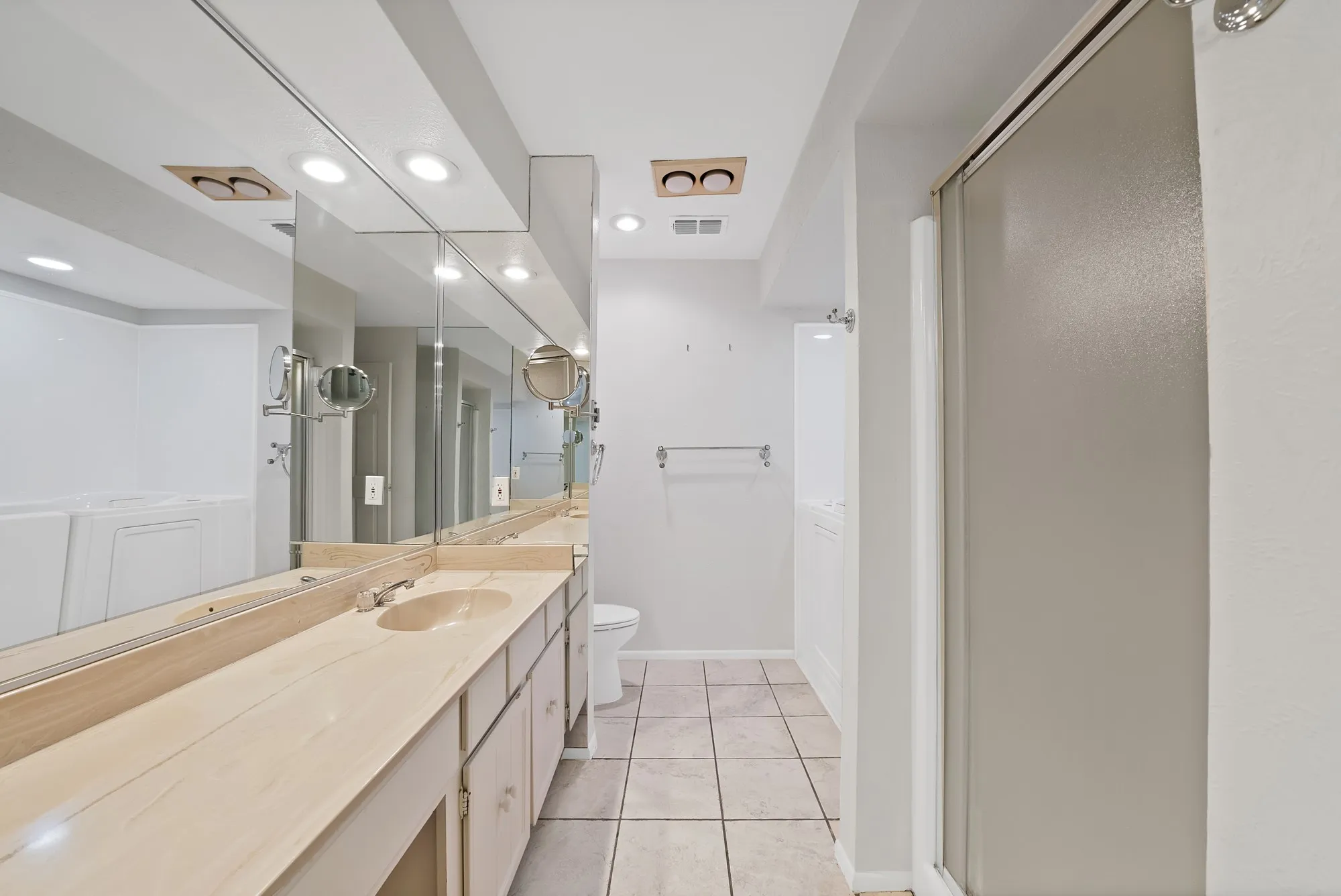 Bathroom featuring a dual vanity with light-toned countertops, integrated sinks, and extensive mirror coverage