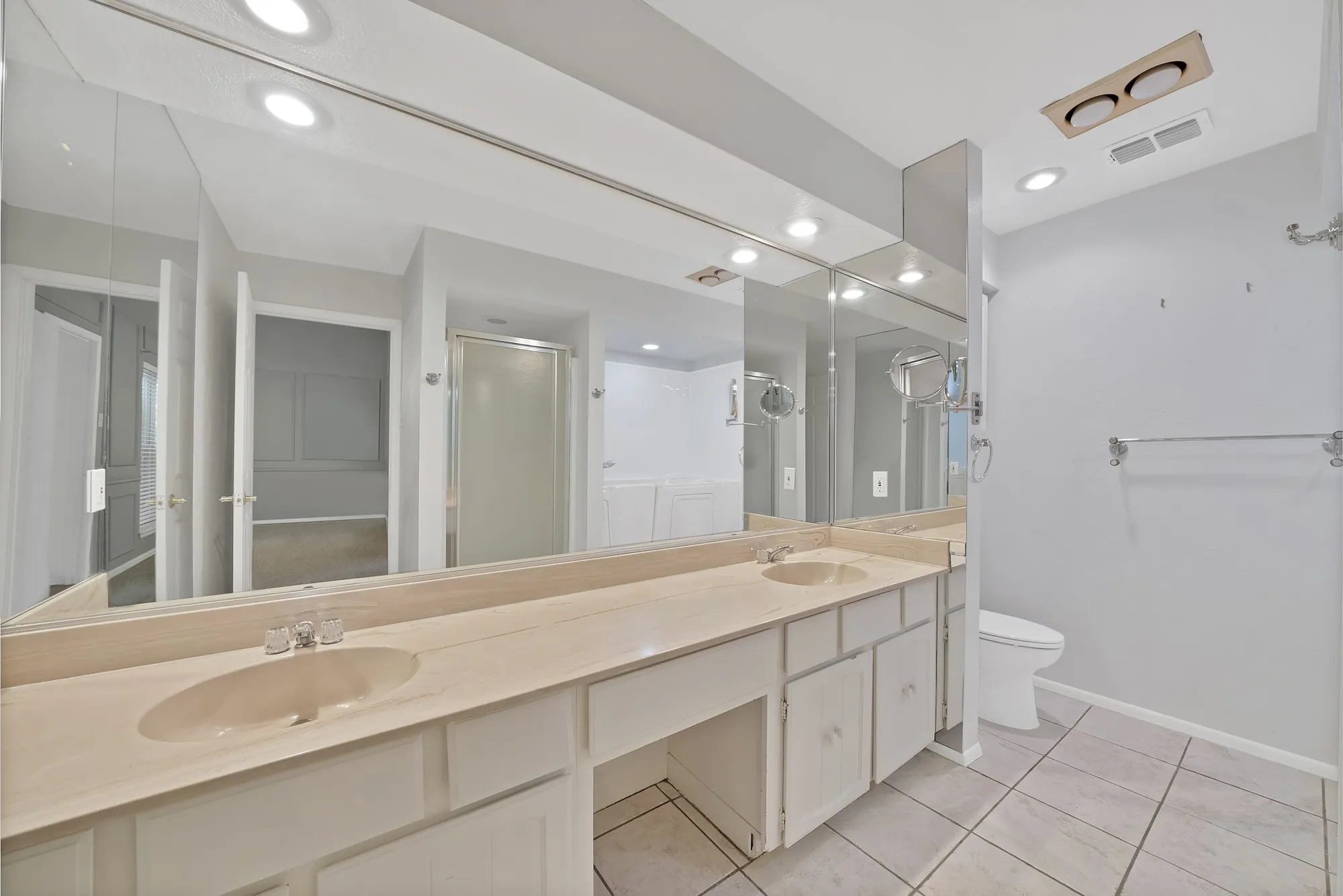 Bathroom featuring a double vanity with integrated sinks, a lengthy mirror, recessed lighting, and tile flooring