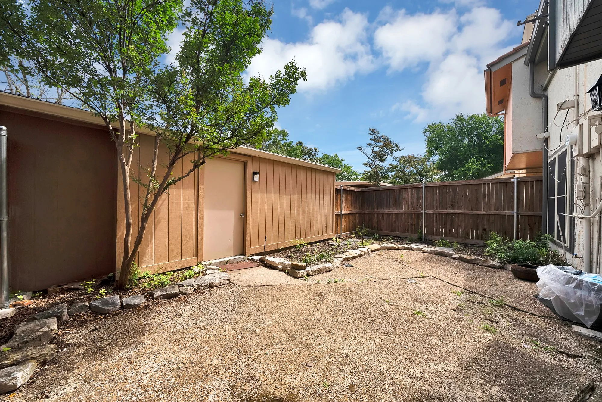 Enclosed private yard featuring a wood privacy fence and a detached storage structure