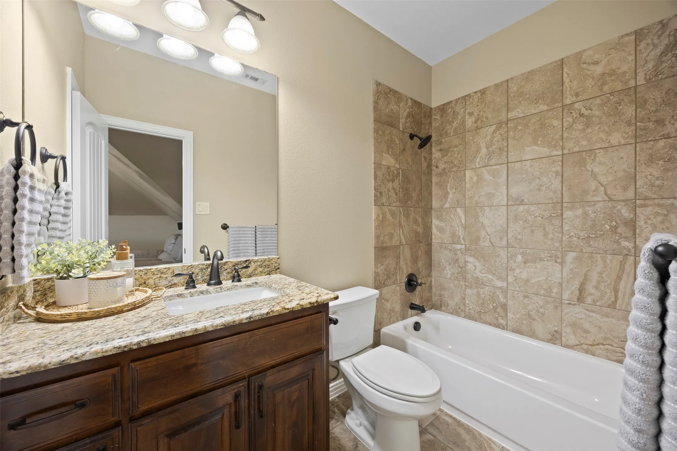 Bathroom featuring a dark wood-finish vanity with a light-toned stone countertop, an integrated sink, and dark-finish fixtures