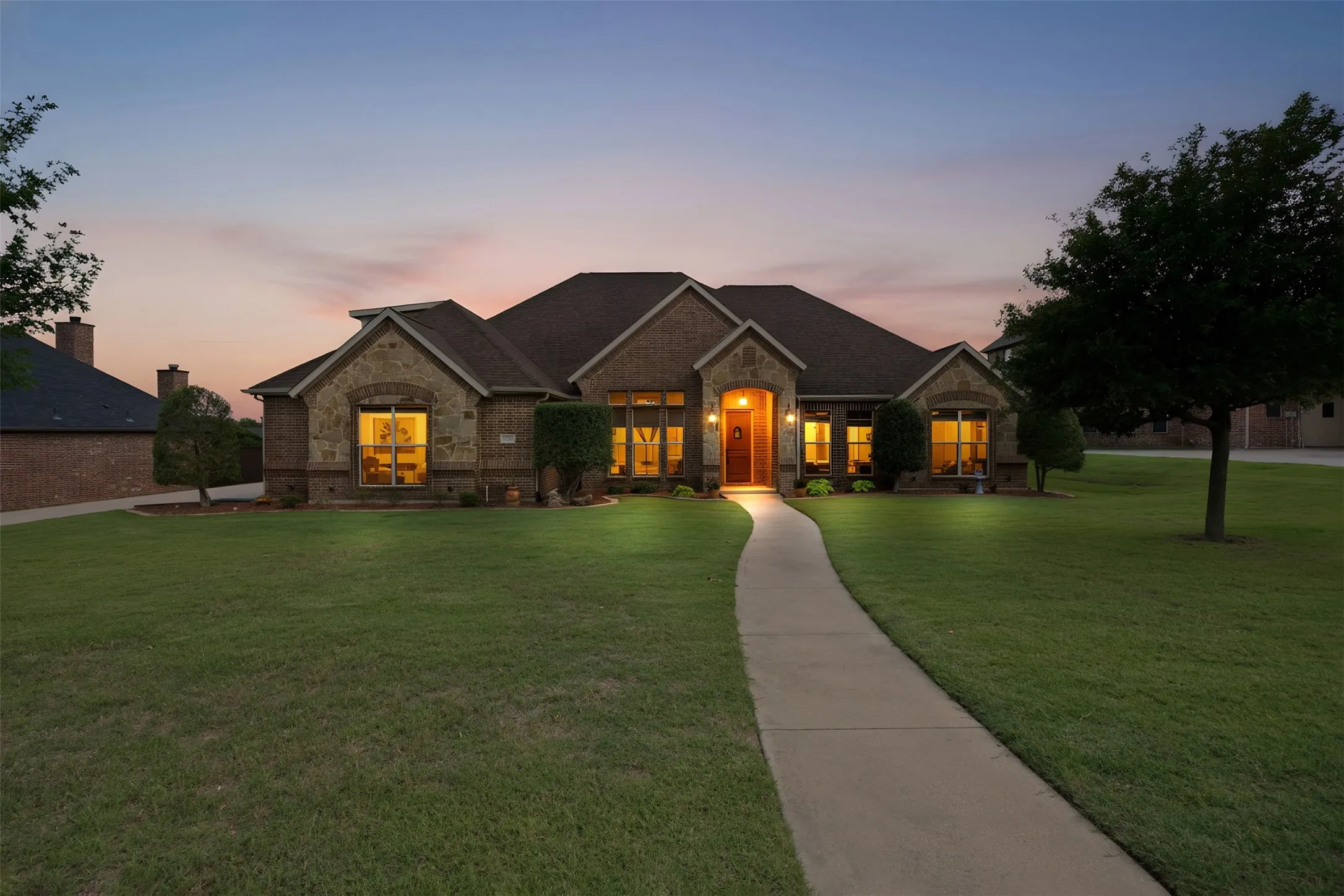 Brick and stone facade residence featuring multiple gables and a dark shingle roof