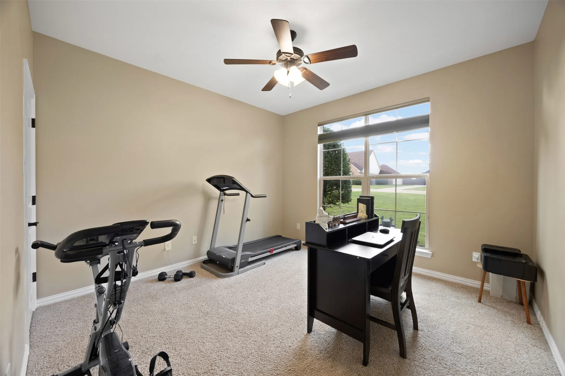 Carpeted room featuring a large window, neutral wall paint, and a ceiling fan with integrated lighting