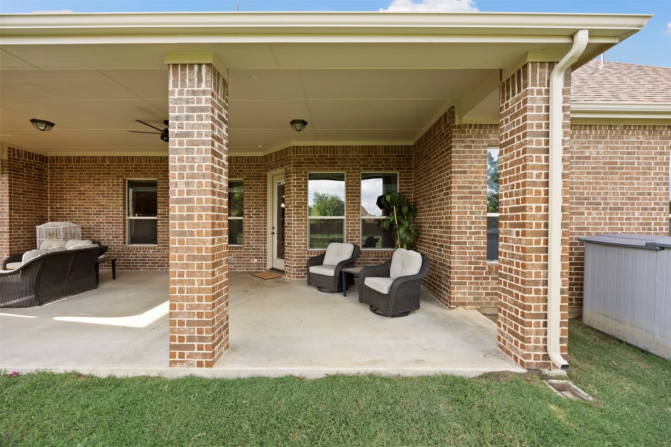 Expansive covered patio featuring brick columns, a concrete slab, and a ceiling fan