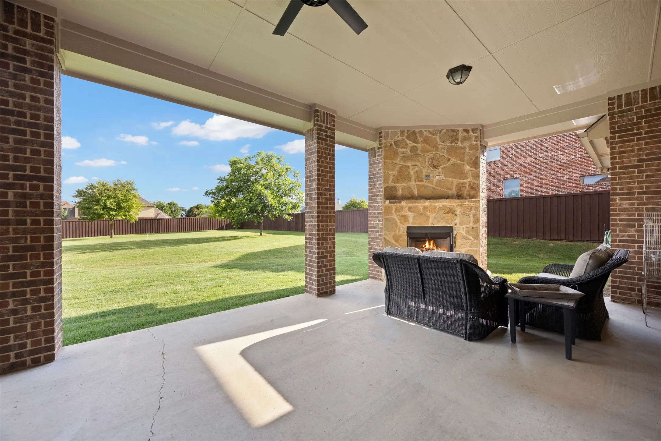 Covered patio featuring a stone fireplace, overhead ceiling fan, and recessed lighting