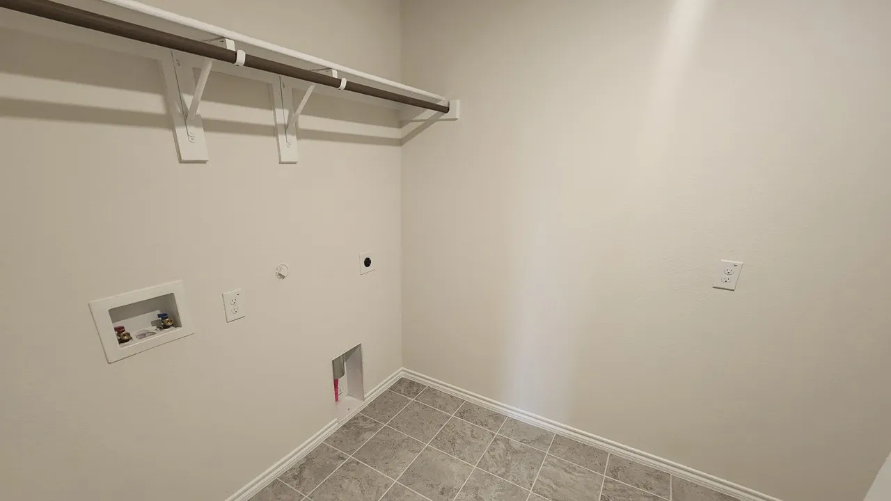 Utility area featuring a clothes hanging rod, tile flooring, and light neutral wall paint