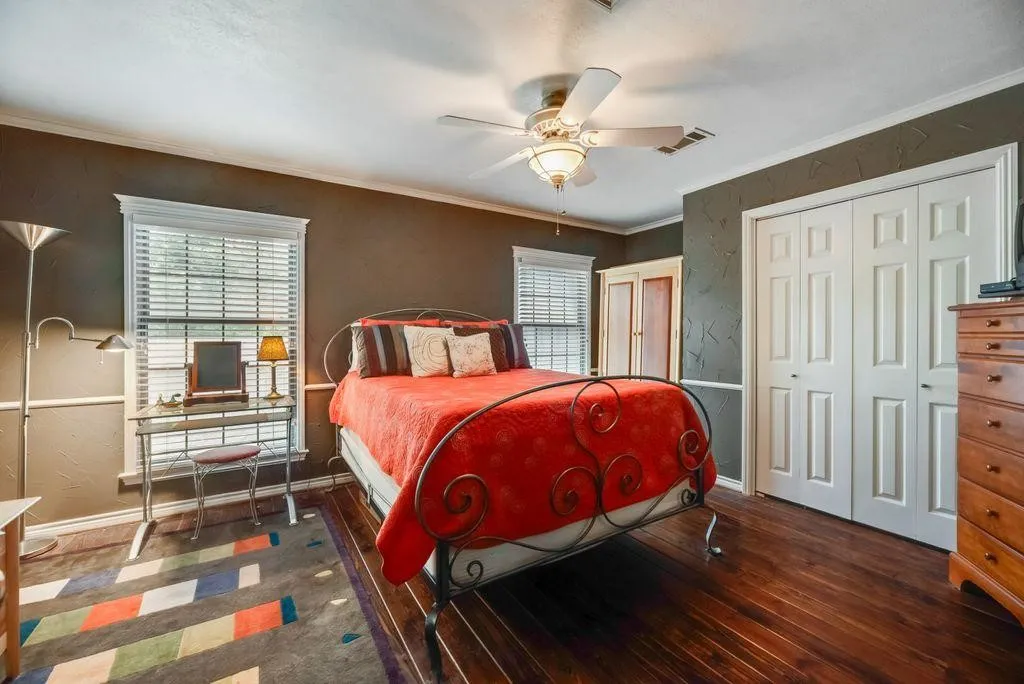 Room featuring hardwood flooring, white baseboards, crown molding, and a ceiling fan