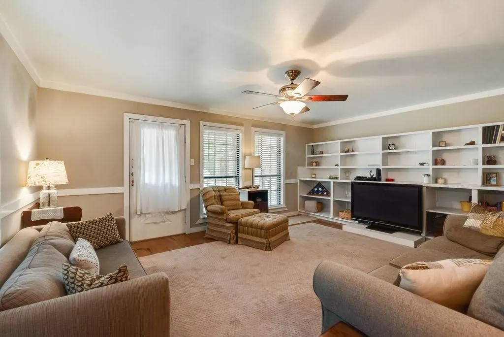 Spacious living area featuring extensive built-in shelving, crown molding, and wainscoting details