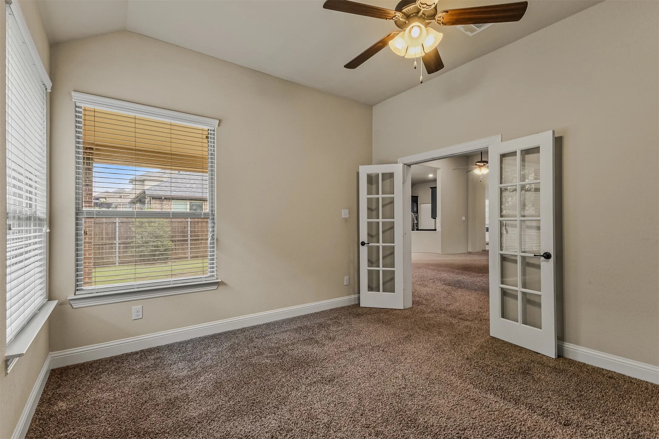 Room featuring vaulted ceilings, plush carpet flooring, and a ceiling fan with light fixture