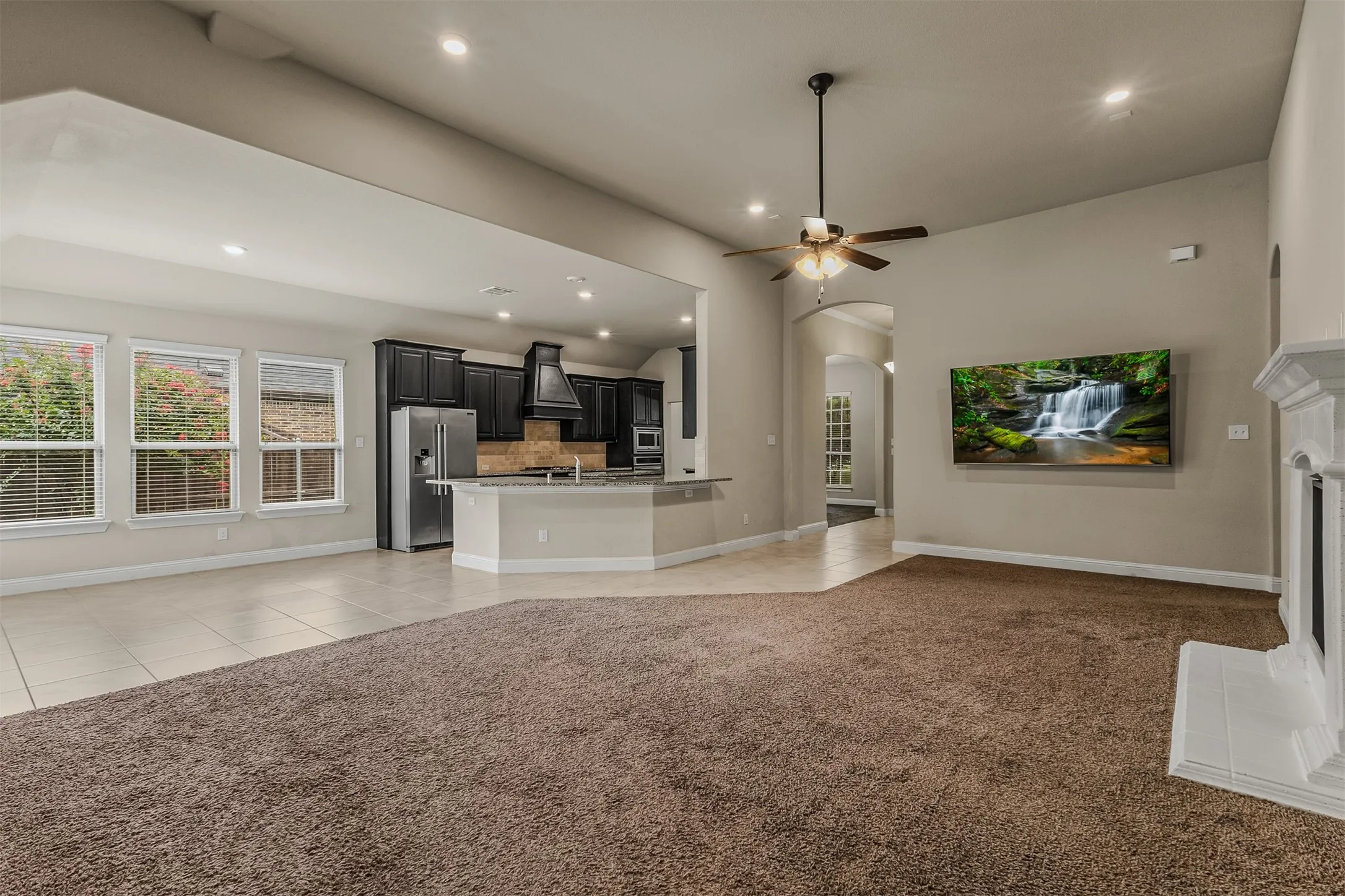 Spacious living area featuring a fireplace with a white mantel, recessed lighting, and a ceiling fan