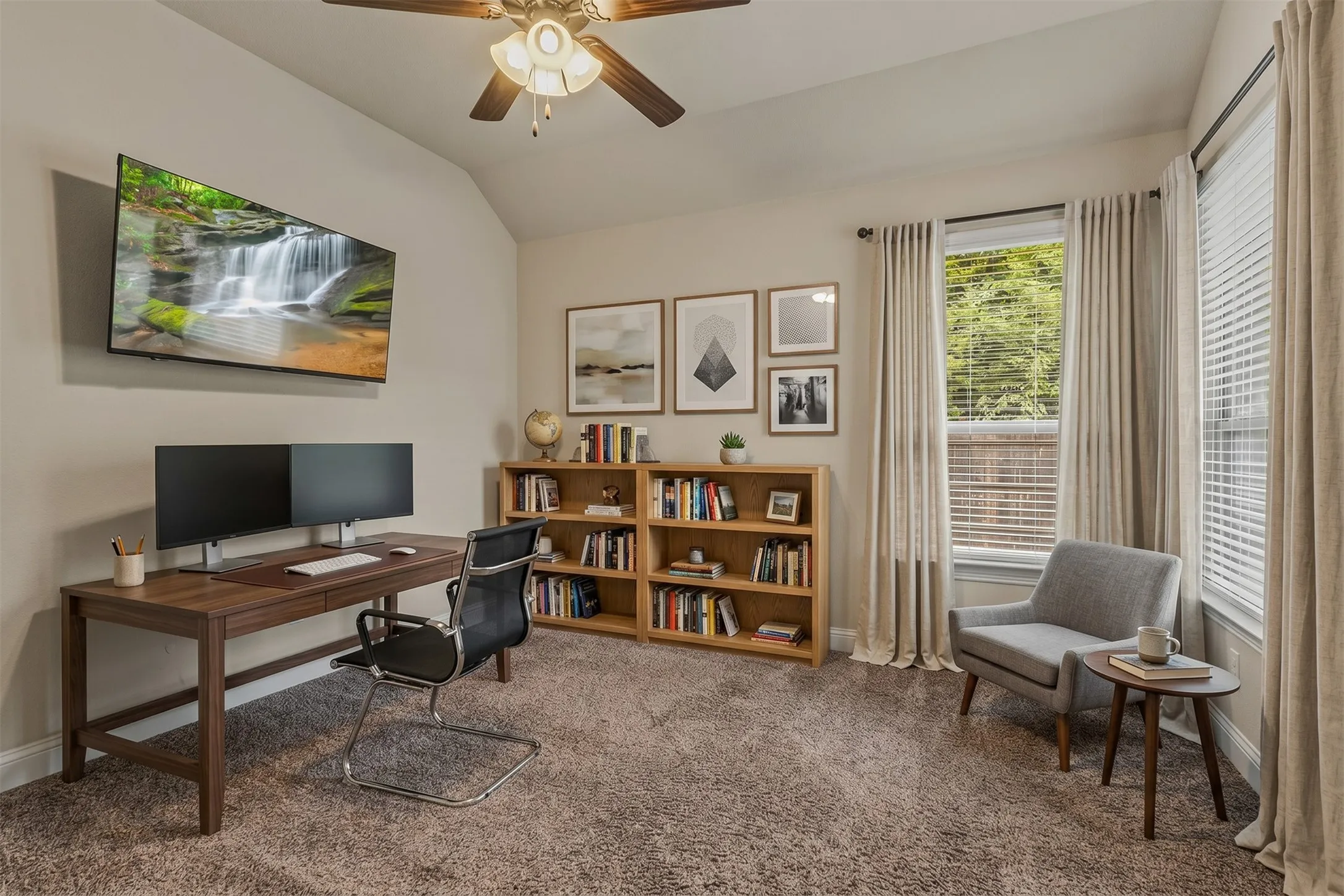 Carpeted room with a vaulted ceiling, ceiling fan, and wall-mounted television