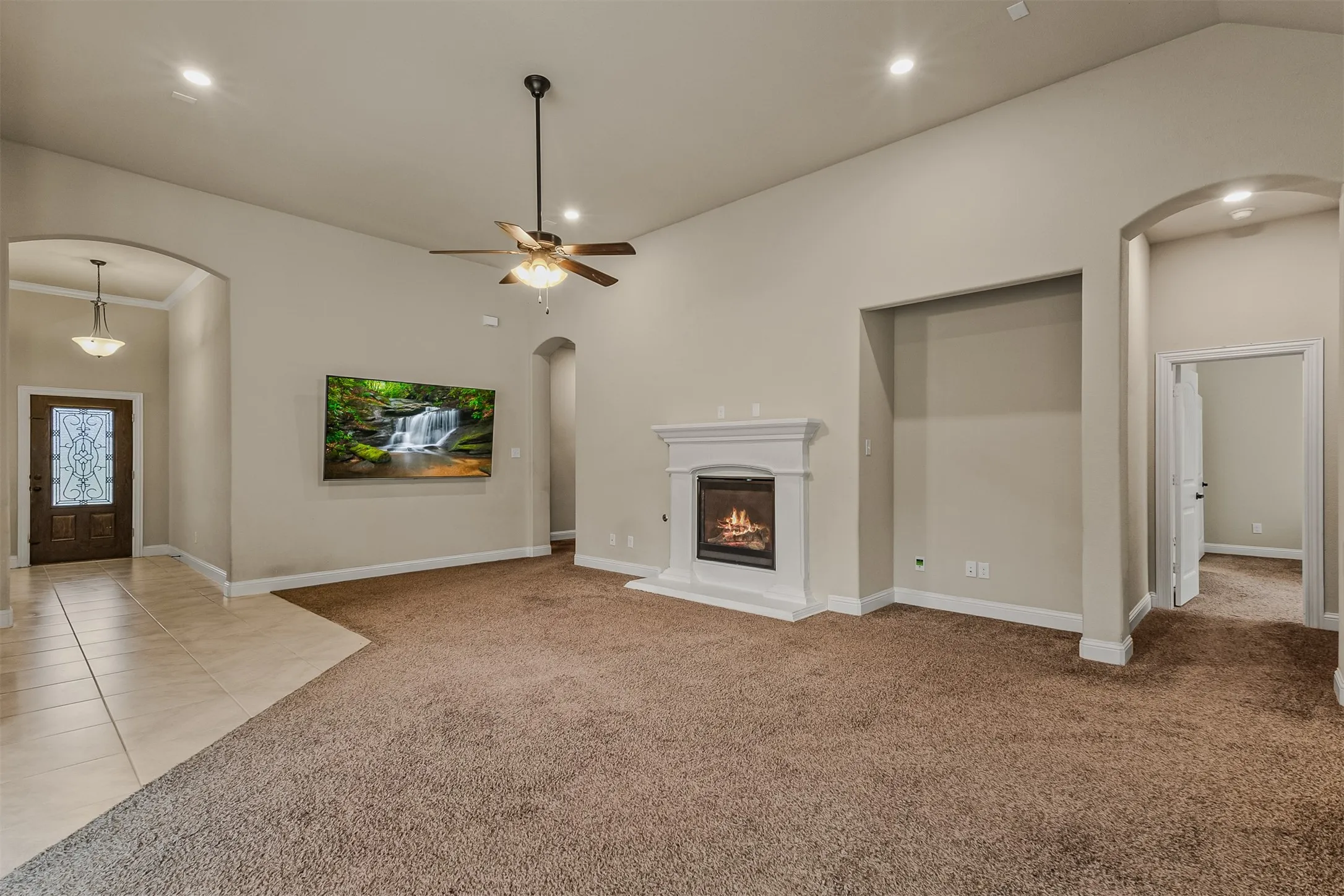 Living area featuring a fireplace with a white mantel, vaulted ceiling, and recessed lighting