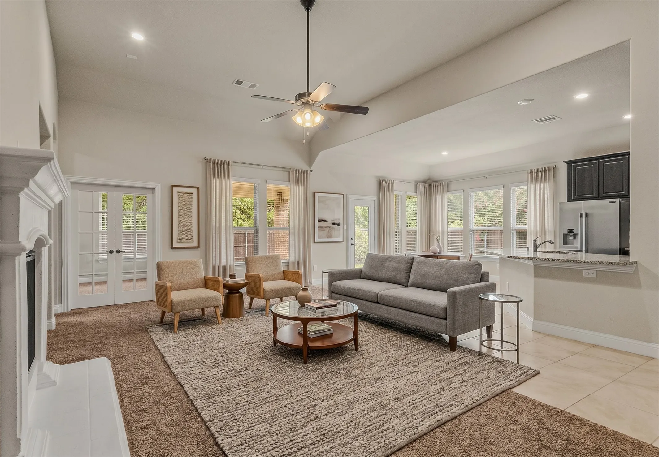 Vaulted ceiling living area featuring a ceiling fan, recessed lighting, and a white fireplace surround