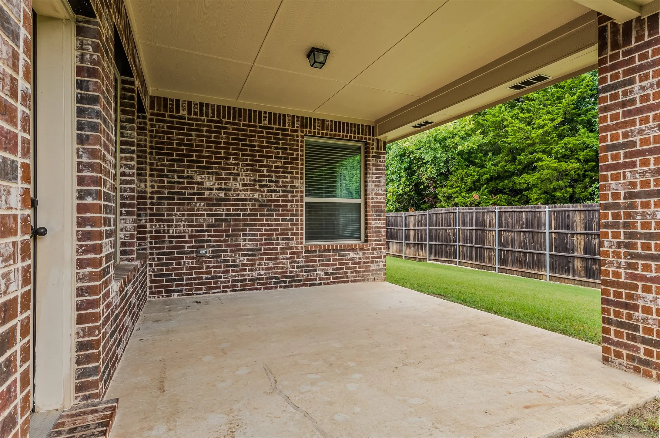 Covered patio with a concrete surface, brick exterior, and recessed lighting