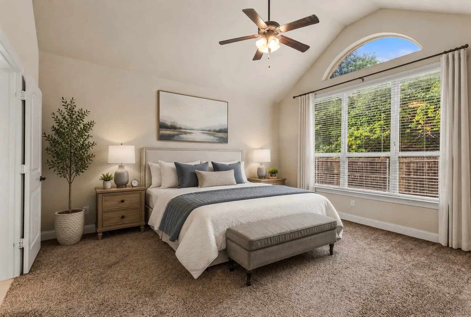 Vaulted ceiling bedroom featuring a large arched window, a multi-pane window with blinds, and soft carpet flooring