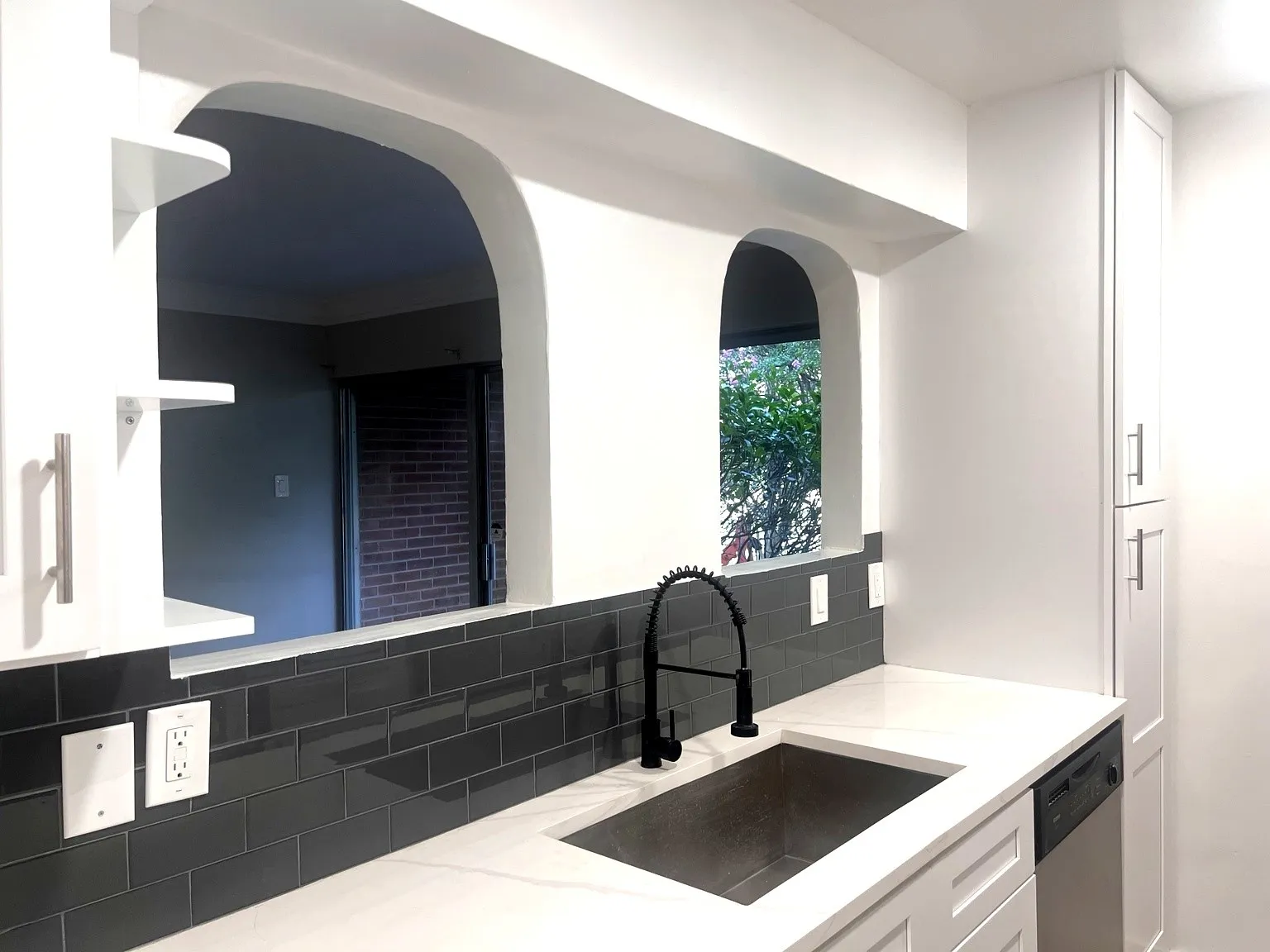 Kitchen featuring white shaker-style cabinetry, a built-in stainless steel sink with a matte black faucet, and a subway tile backsplash