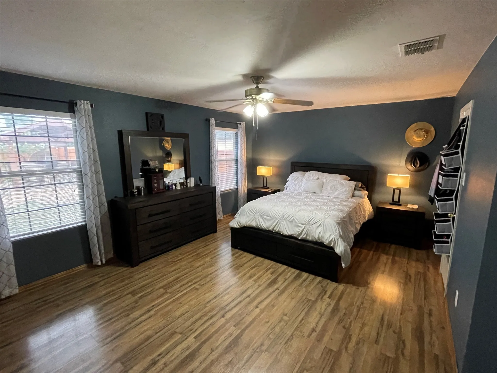 Bedroom with multiple windows, hardwood / wood-style floors, and ceiling fan