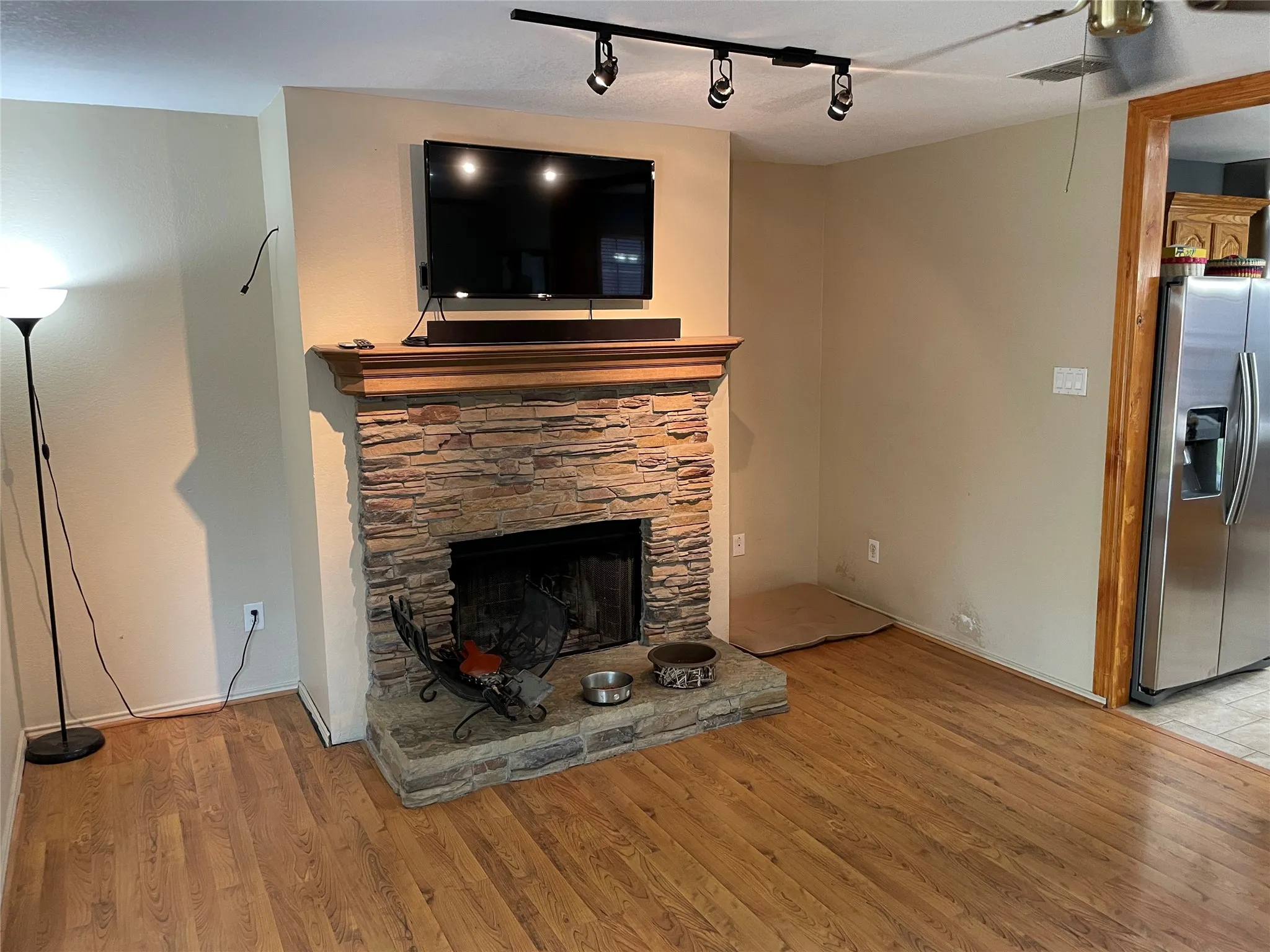 Unfurnished living room featuring a stone fireplace, track lighting, and light wood-type flooring