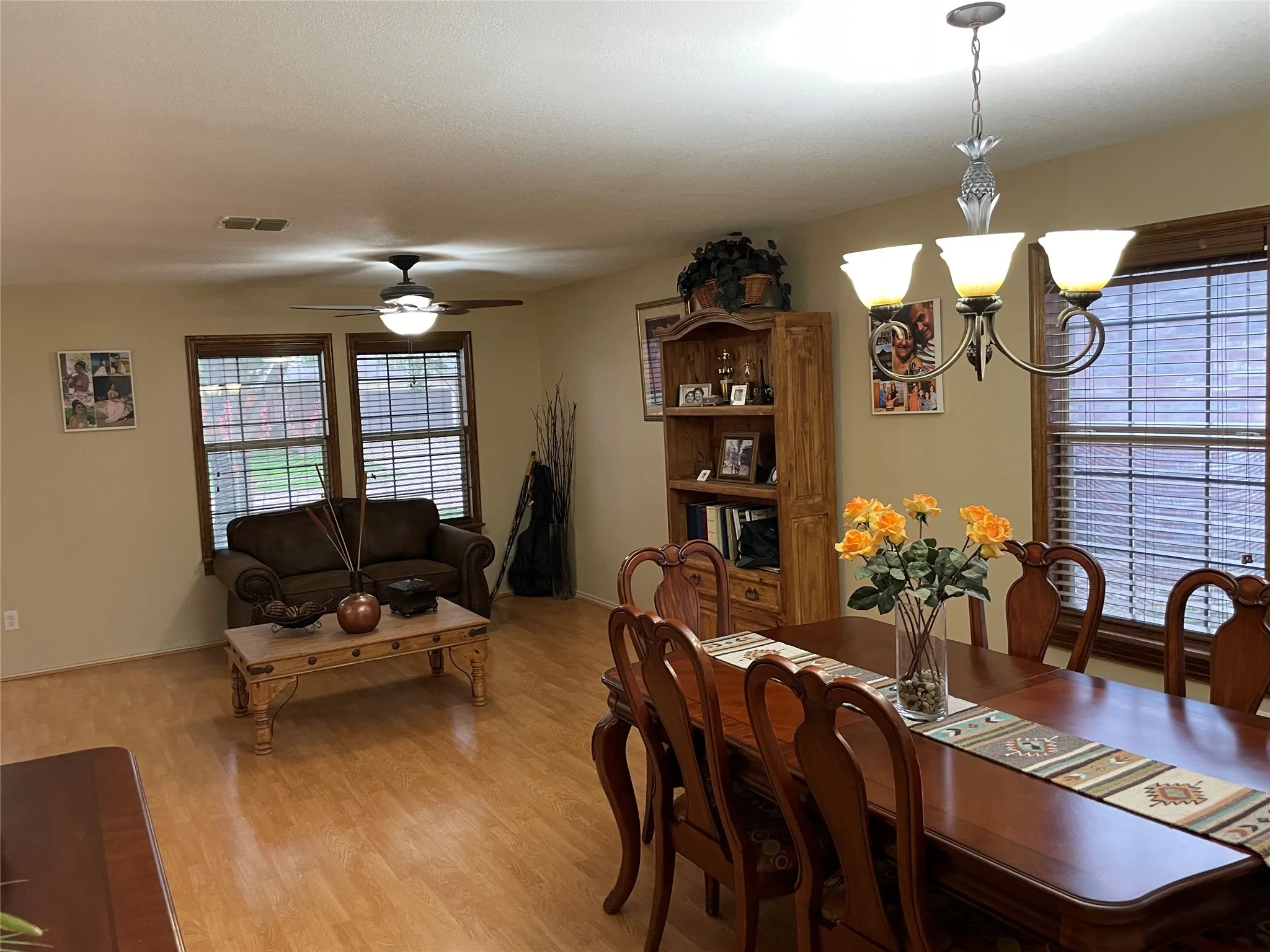 Dining space with ceiling fan with notable chandelier and light wood-type flooring