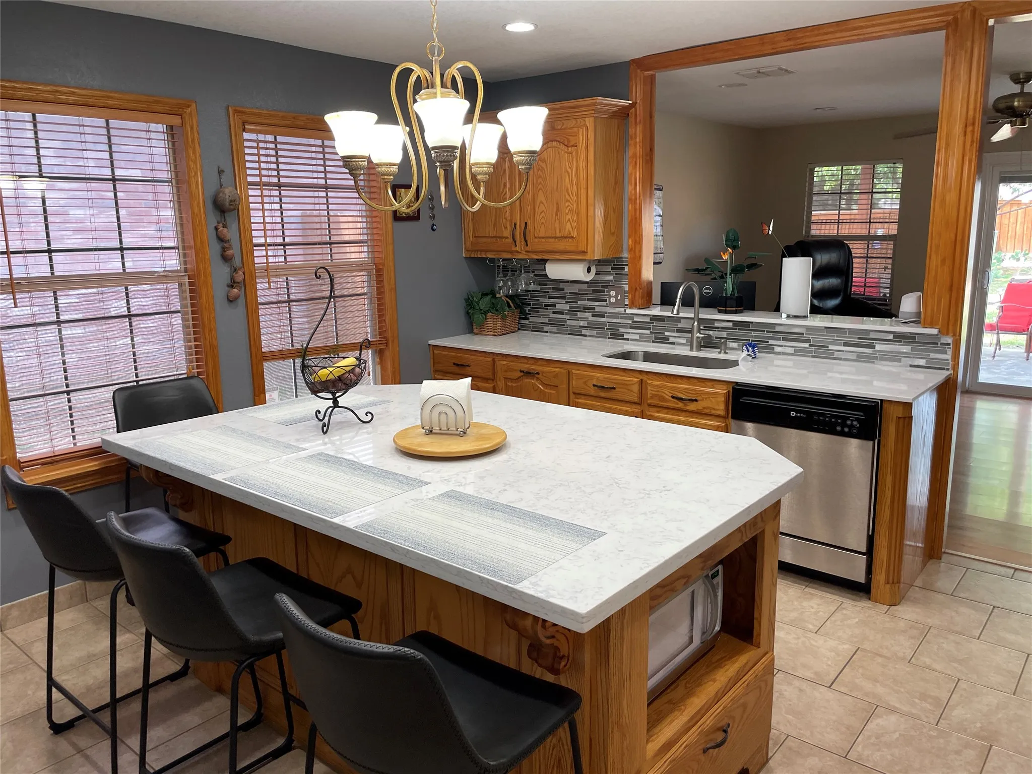 Kitchen featuring decorative backsplash, sink, dishwasher, hanging light fixtures, and light tile patterned flooring
