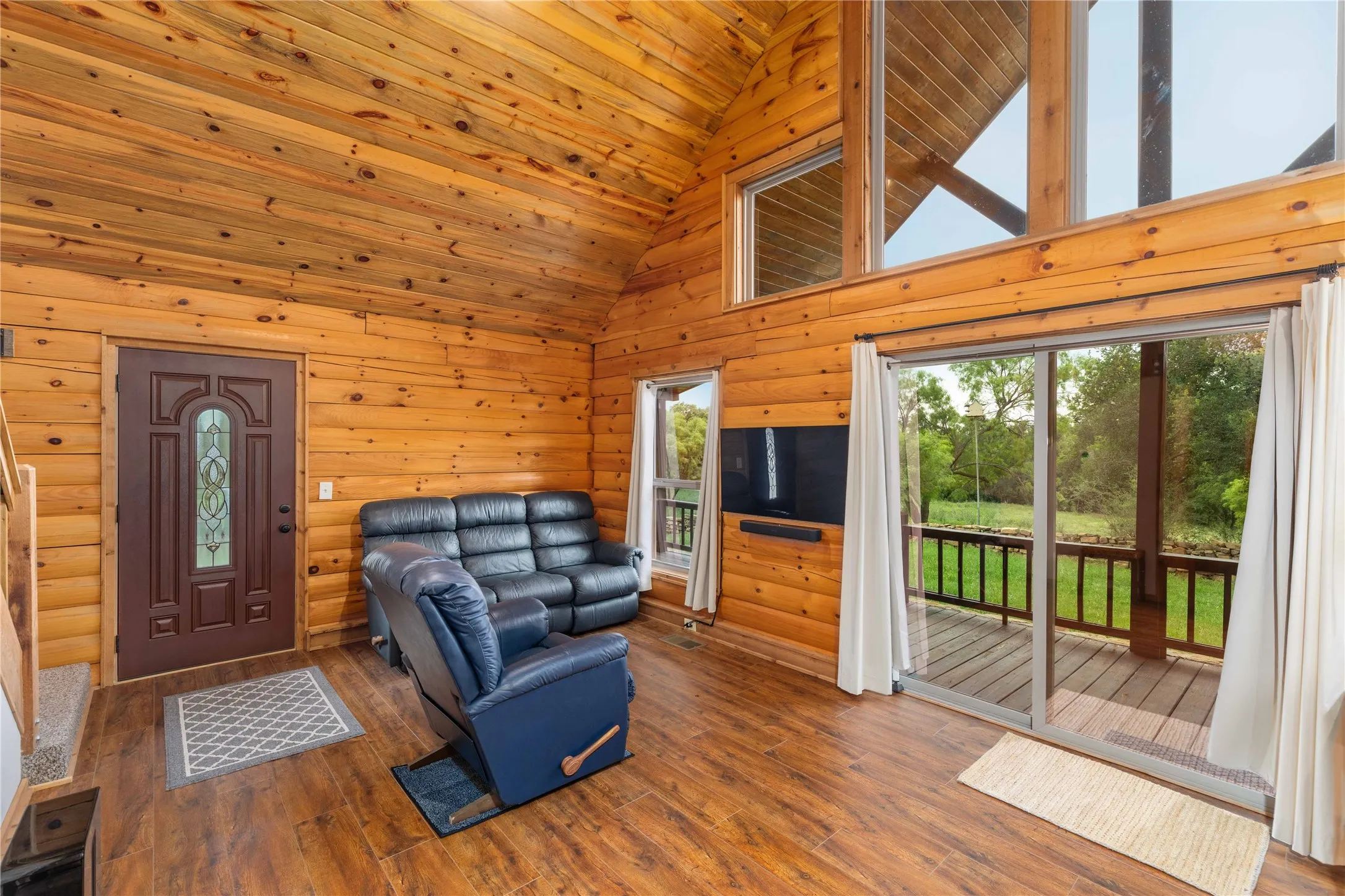 Wood-paneled interior featuring a vaulted ceiling with exposed beams