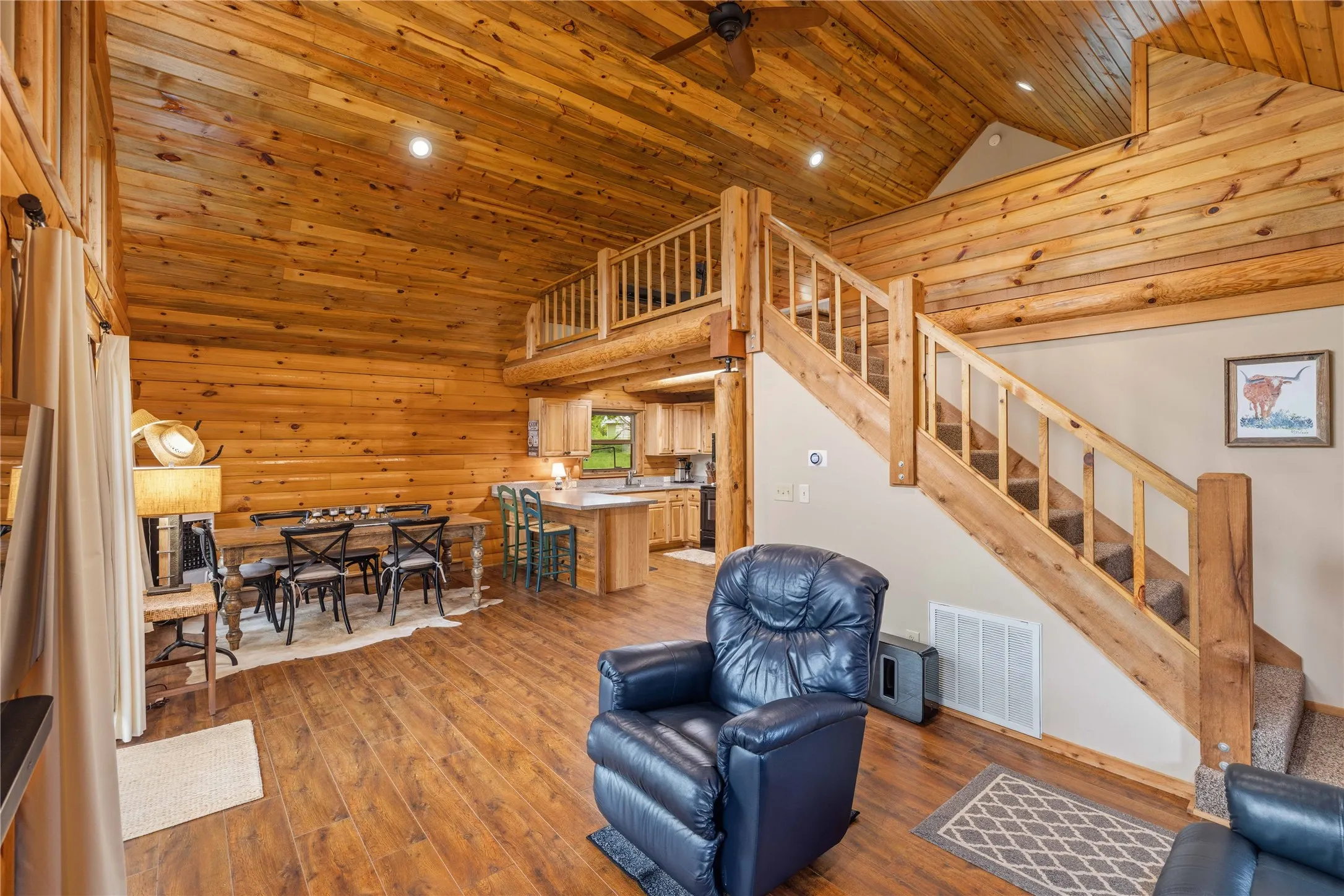 Open-concept living area featuring extensive wood-finish walls and vaulted ceilings