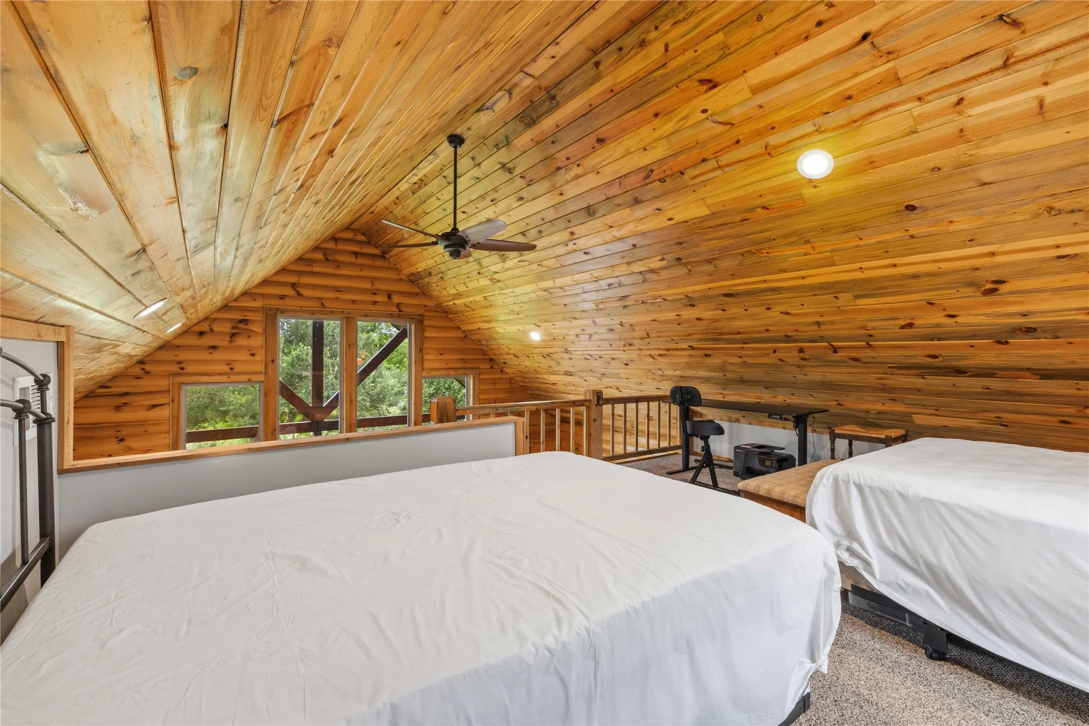 Vaulted wood-paneled ceilings with exposed beams, multiple windows, and a ceiling fan