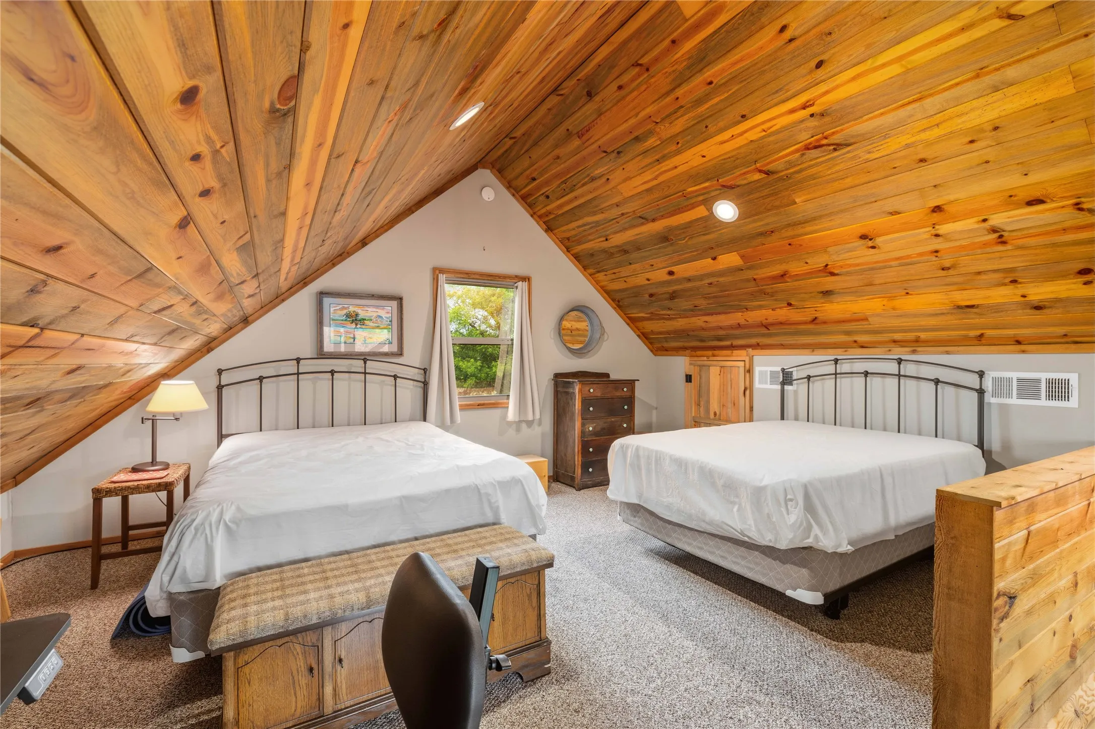 Vaulted wood-paneled ceilings highlight this attic space, featuring recessed lighting, a window with exterior views, and neutral-toned wall paint